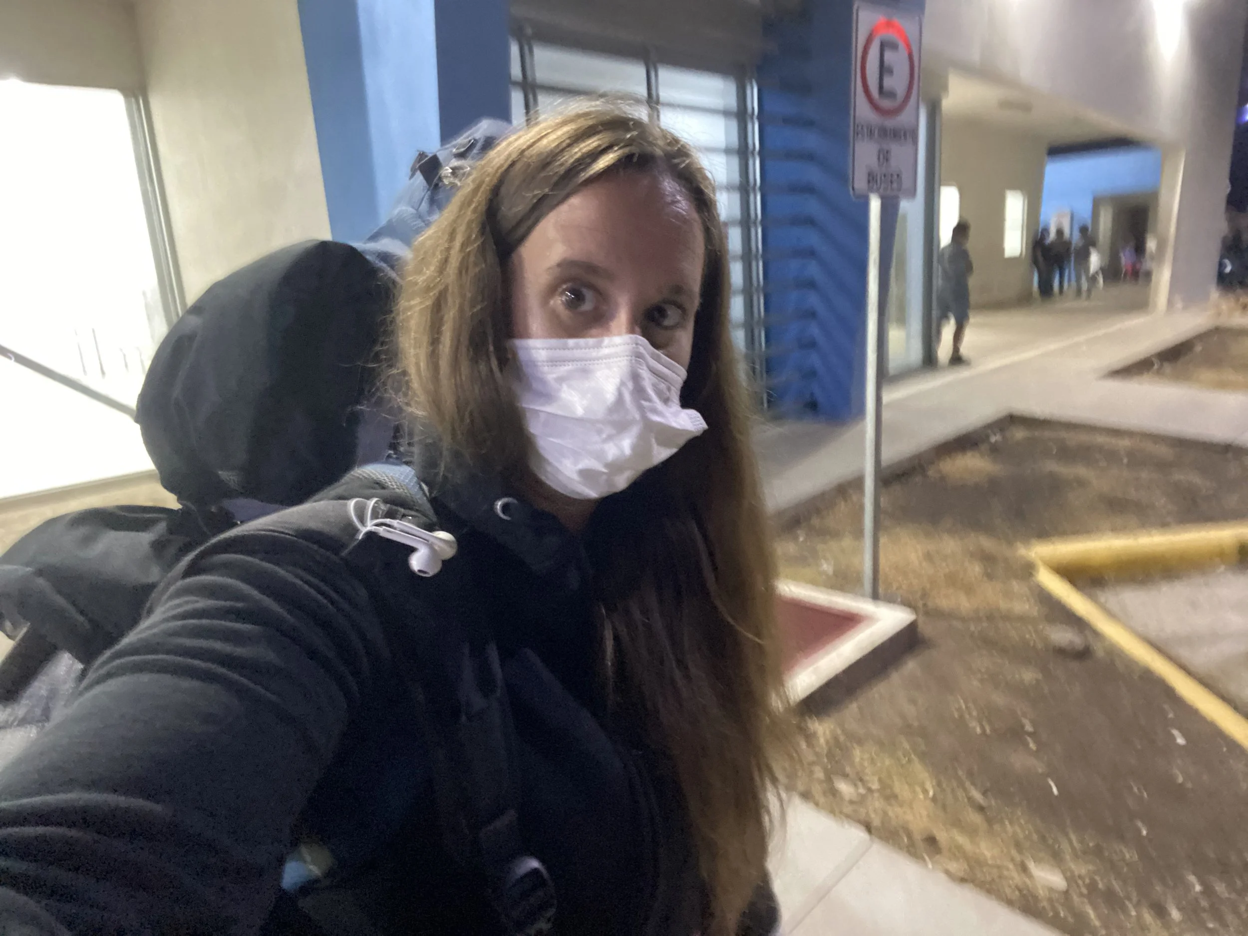 Solo female traveler with backpack wearing a mask while waiting at the Nicaragua border crossing at night