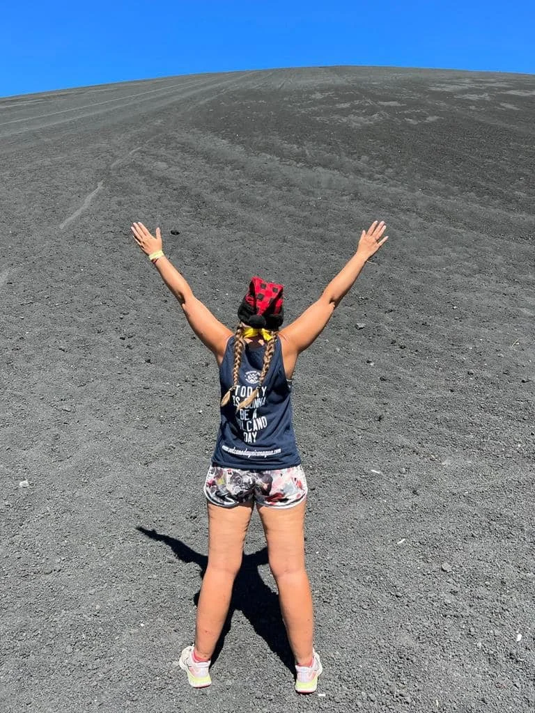 Solo traveler standing at the top of Cerro Negro volcano in Nicaragua showing the steep volcanic slope