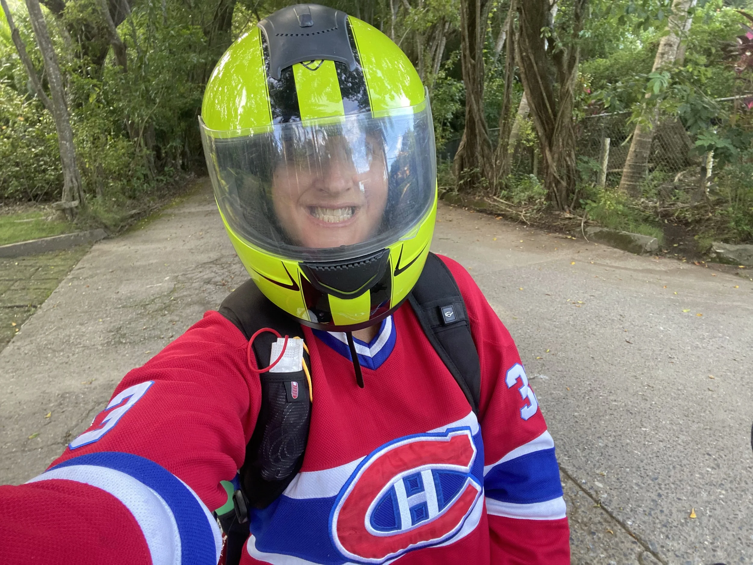 JD wearing a helmet while riding a motorbike in Roatán, Honduras surrounded by tropical jungle