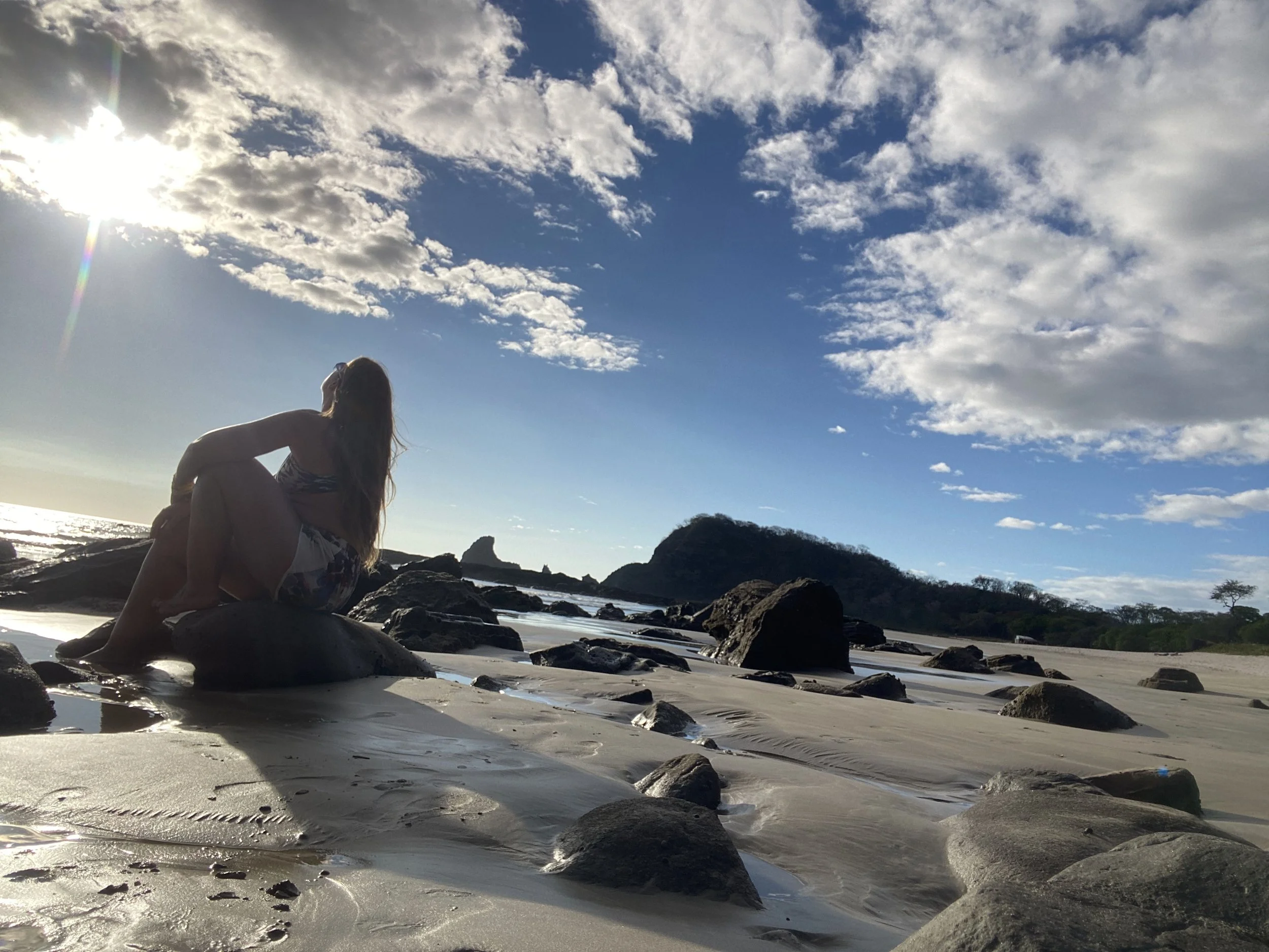 Traveler relaxing on the rocks at Playa Hermosa near San Juan del Sur, Nicaragua, the day before Sunday Funday.