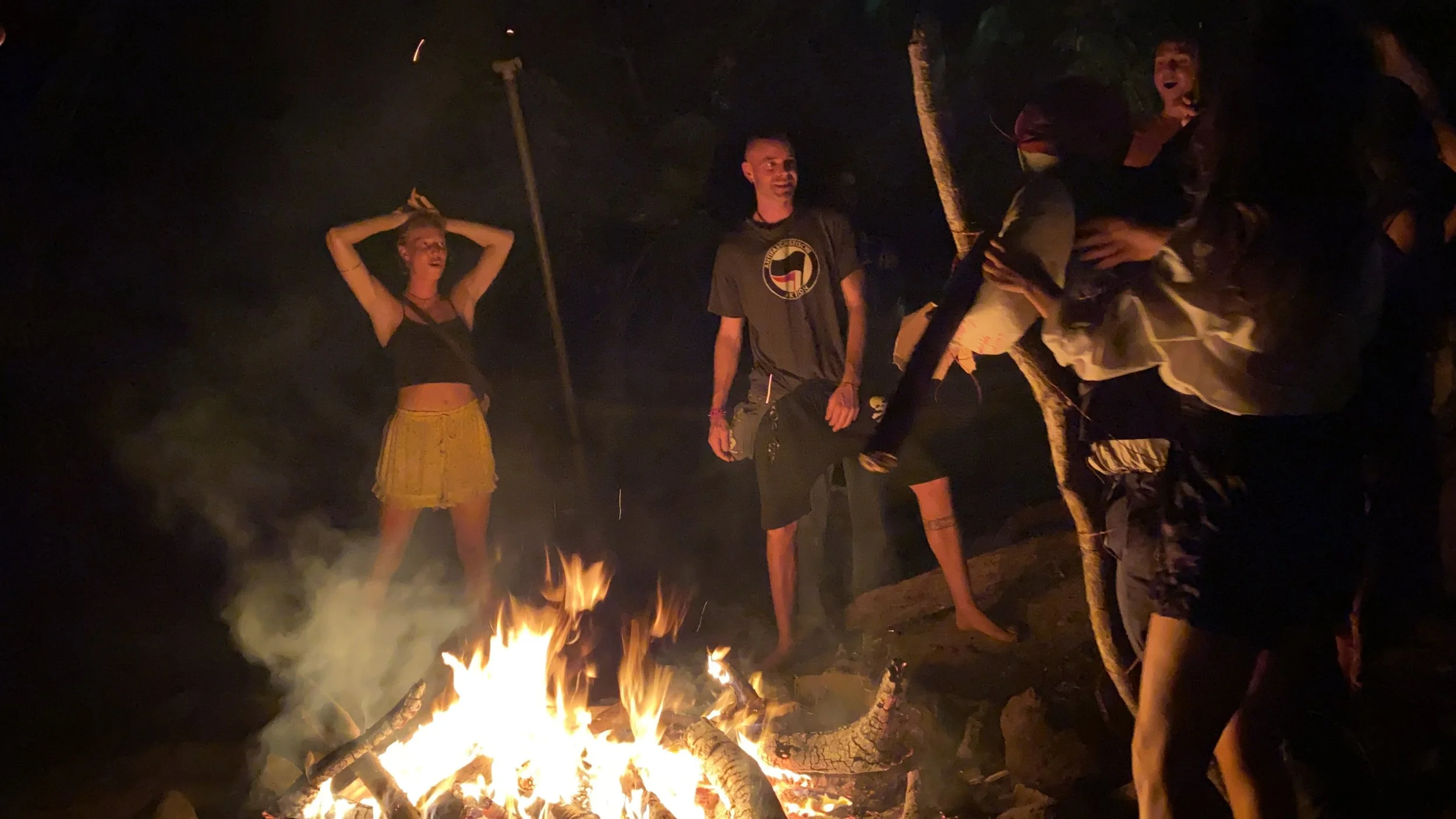 Backpackers gathered around a bonfire at night on Ometepe Island during a New Year’s Eve celebration.