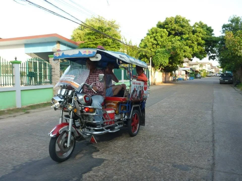 Colorful tuk-tuk driving down a street, representing a popular form of local transportation that travelers should agree on the price for before starting the ride.