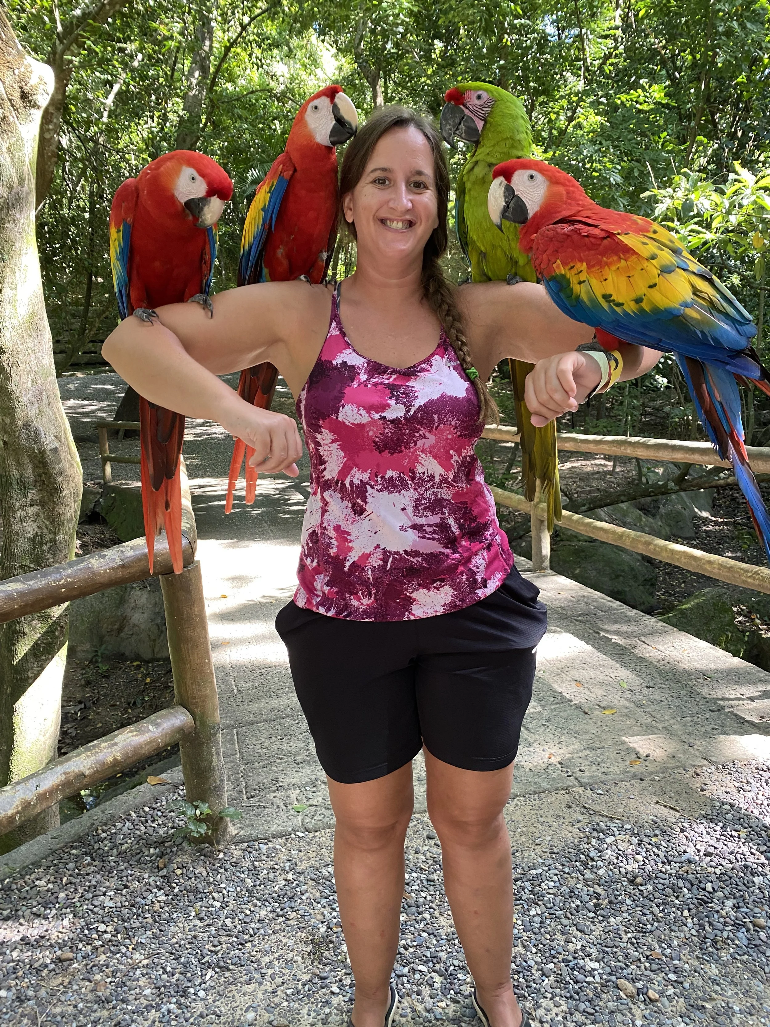 Woman posing with colorful macaws at Gumbalimba Park in Roatán, Honduras