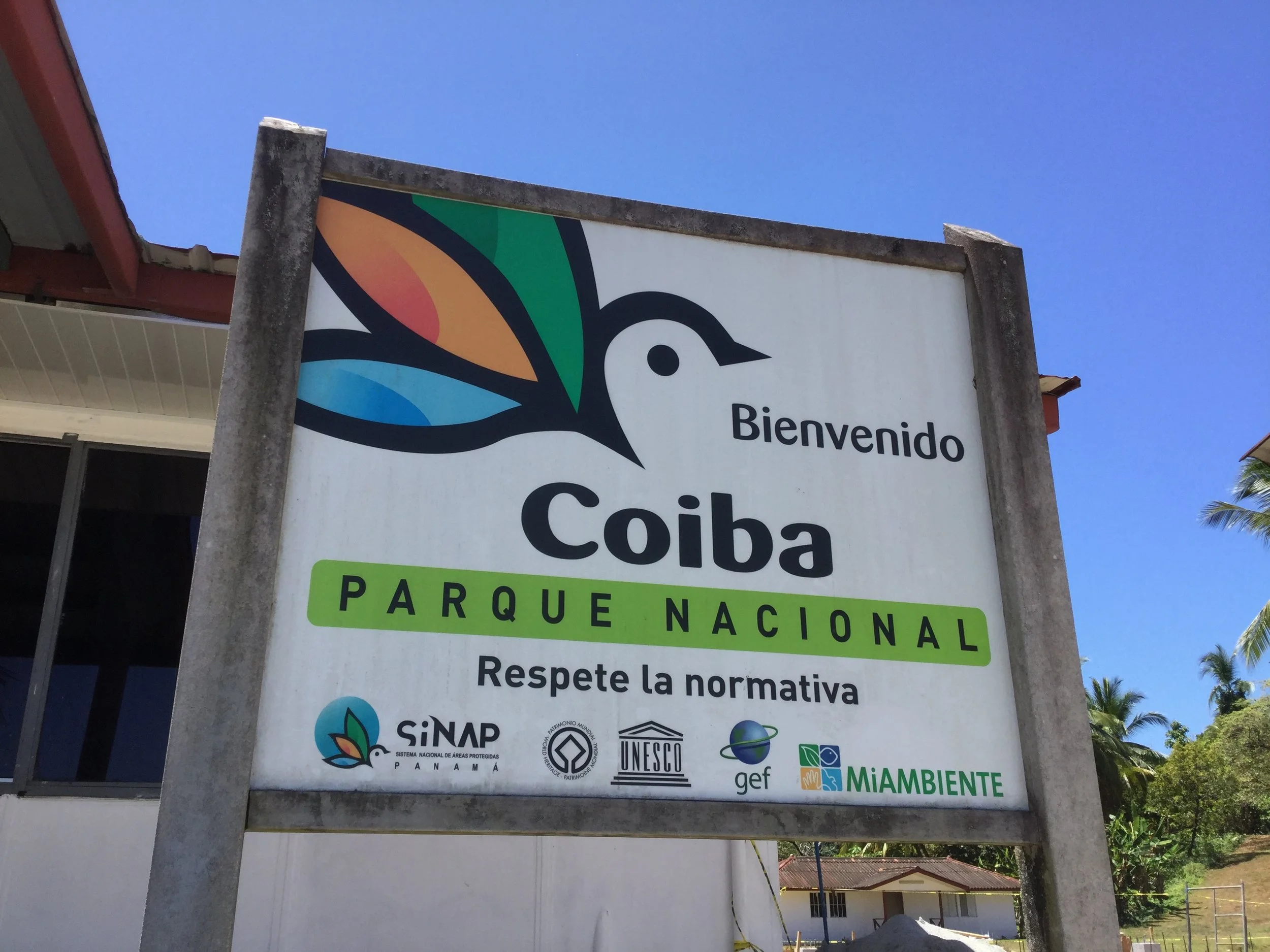 Welcome sign for Coiba National Park in Panama beneath a clear blue sky.