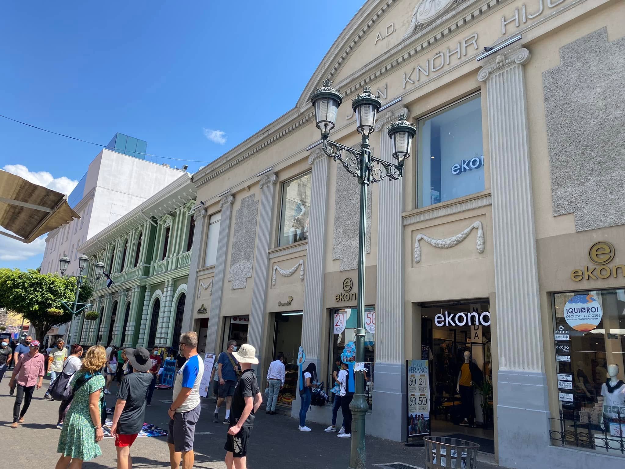 Crowded pedestrian shopping street with stores, street vendors, and historic buildings along Avenida Central in San José.