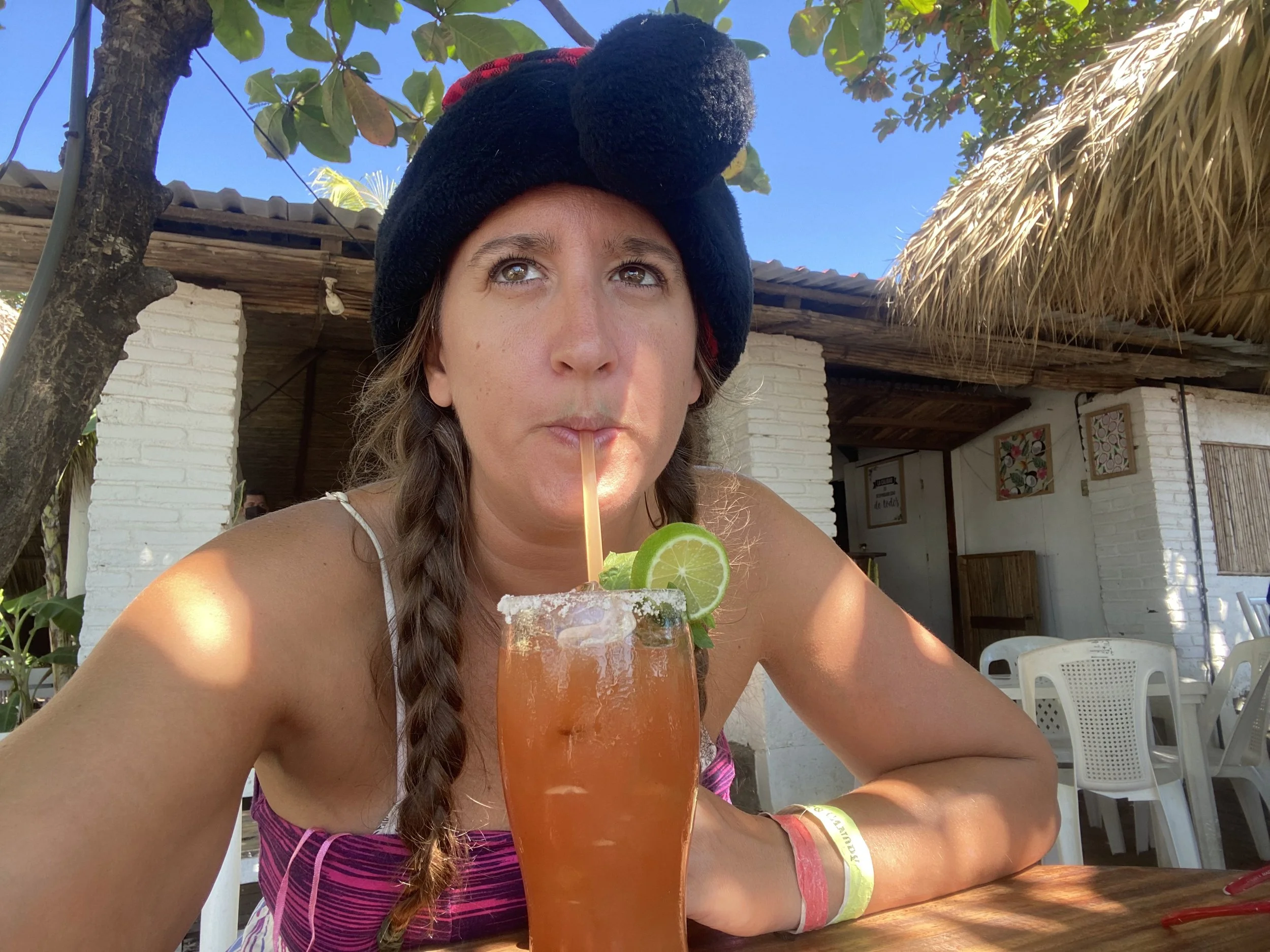 Solo female traveler sitting at a beachside restaurant in Nicaragua drinking a Caesar cocktail on Christmas Day