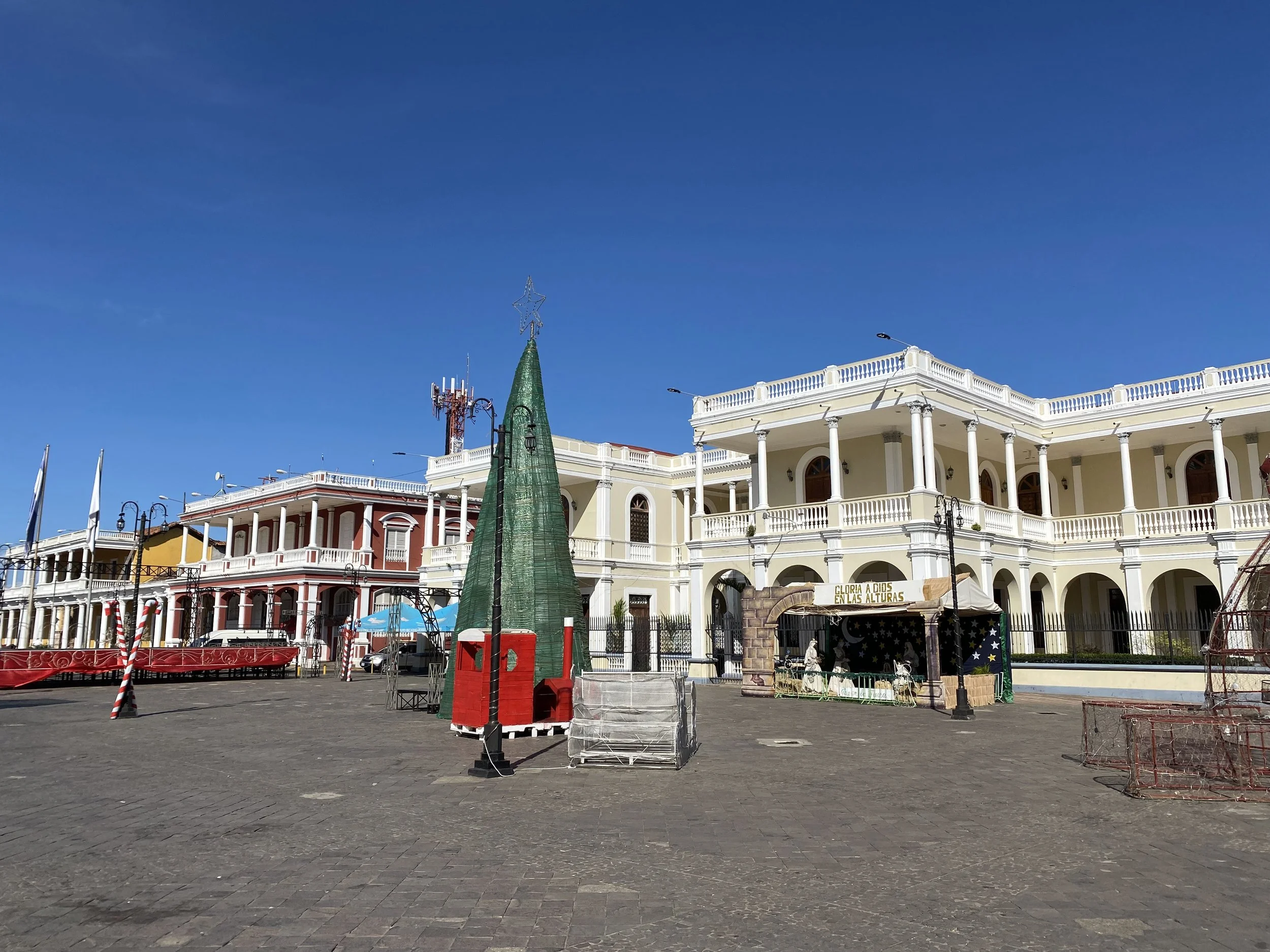Open plaza in Granada, Nicaragua with colonial buildings, a central square, and a decorative Christmas tree under a clear blue sky.