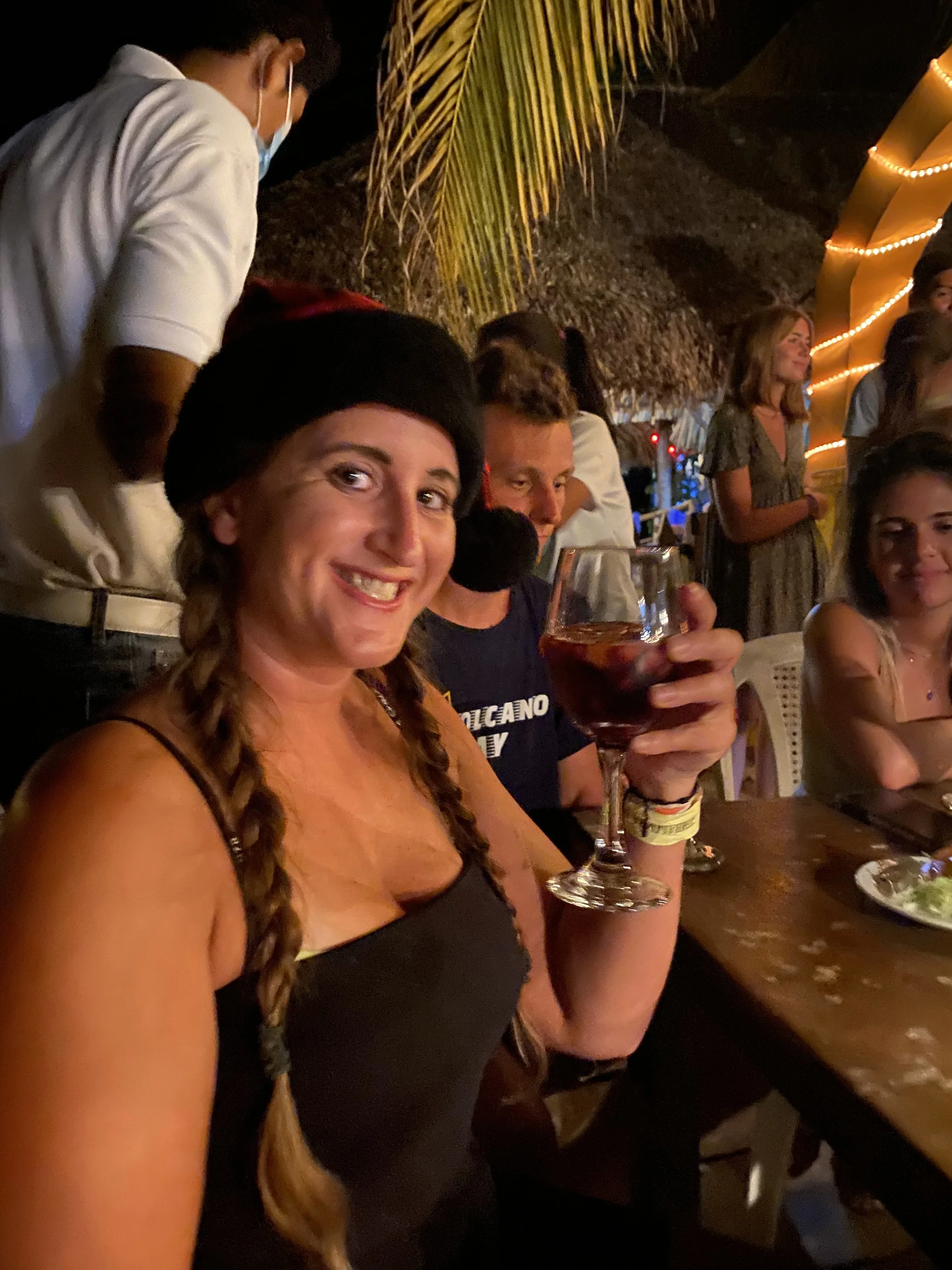 Solo female traveler enjoying a glass of wine during a Christmas Eve dinner with other travelers in Las Peñitas, Nicaragua
