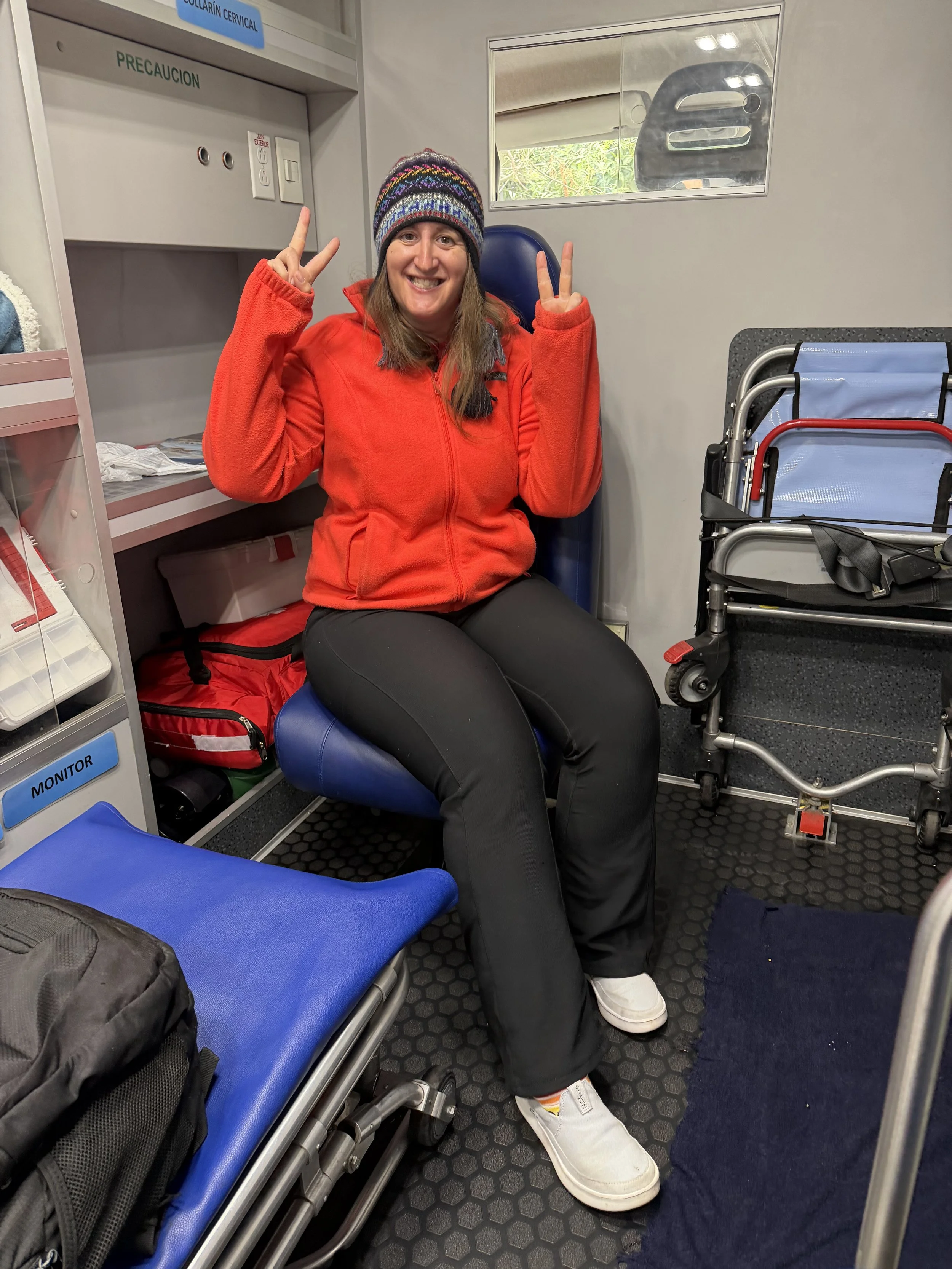 Solo female traveler sitting in an ambulance in Peru after a hiking injury, illustrating the importance of having travel insurance for unexpected medical emergencies abroad.