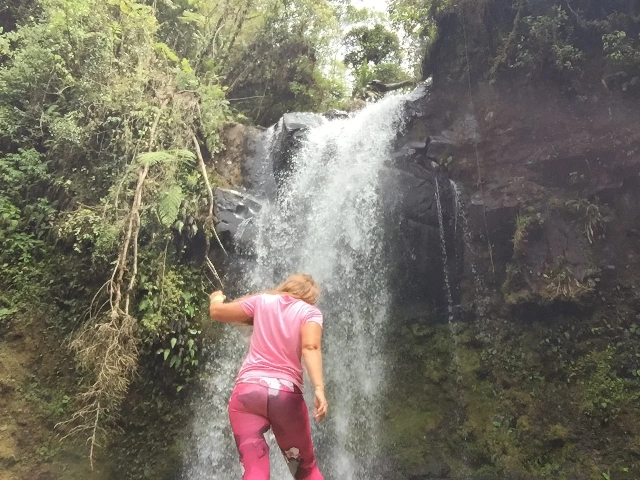 Solo female traveller standing in front of a waterfall surrounded by lush rainforest near Boquete, Panama.