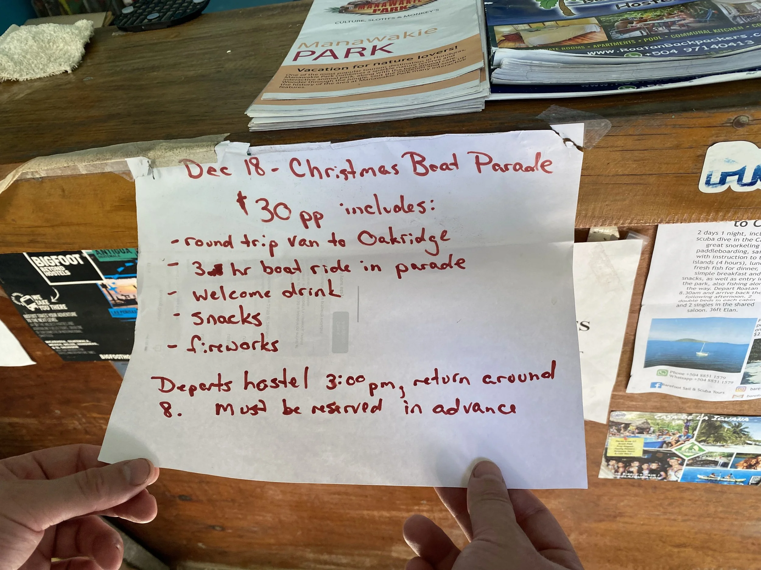 Handwritten sign advertising a Christmas boat parade tour in Roatán, Honduras with price and details listed