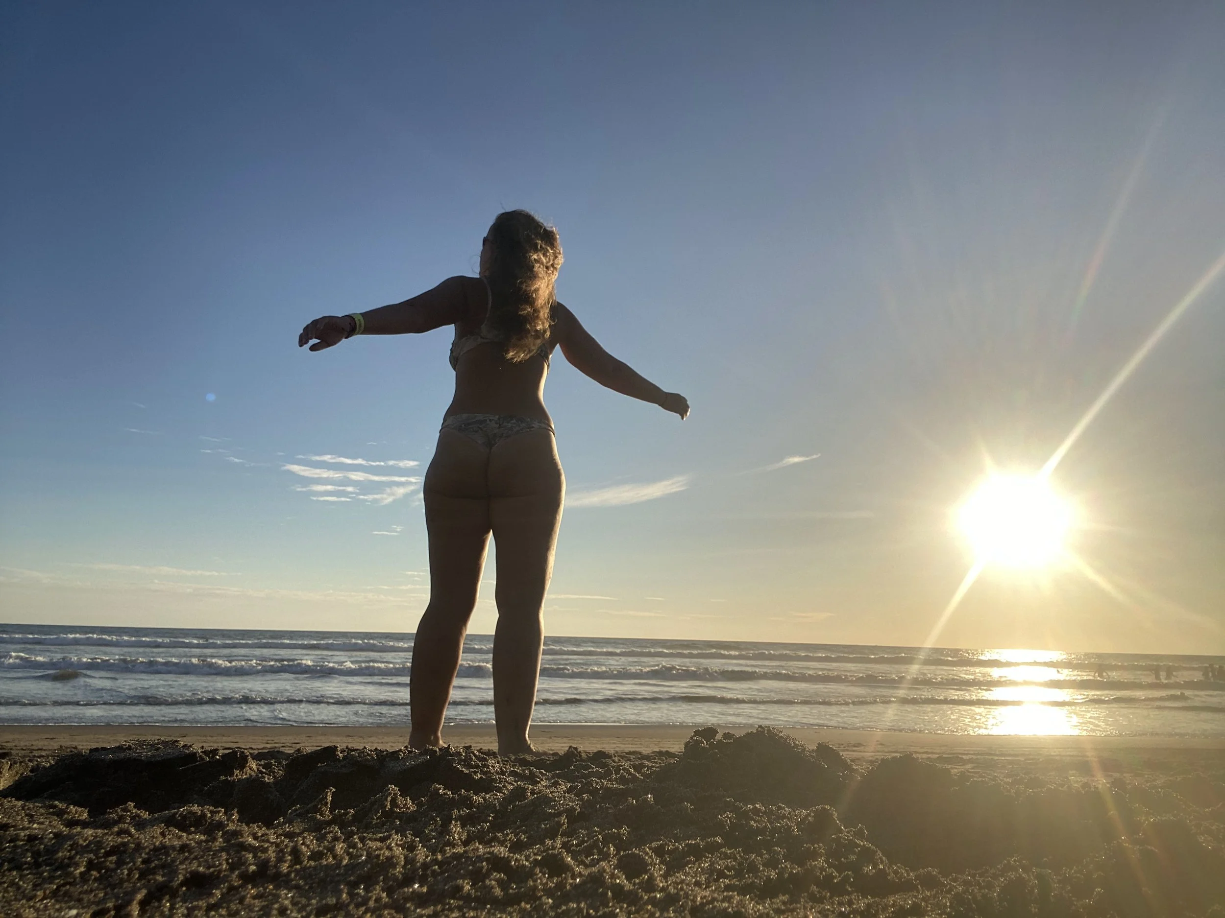 Solo female traveler standing on a beach in Nicaragua at sunset with ocean waves and bright sunny weather
