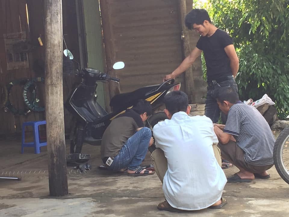 Local mechanics repairing a traveler's motorbike in Sapa, Vietnam after it broke down during a solo backpacking trip.