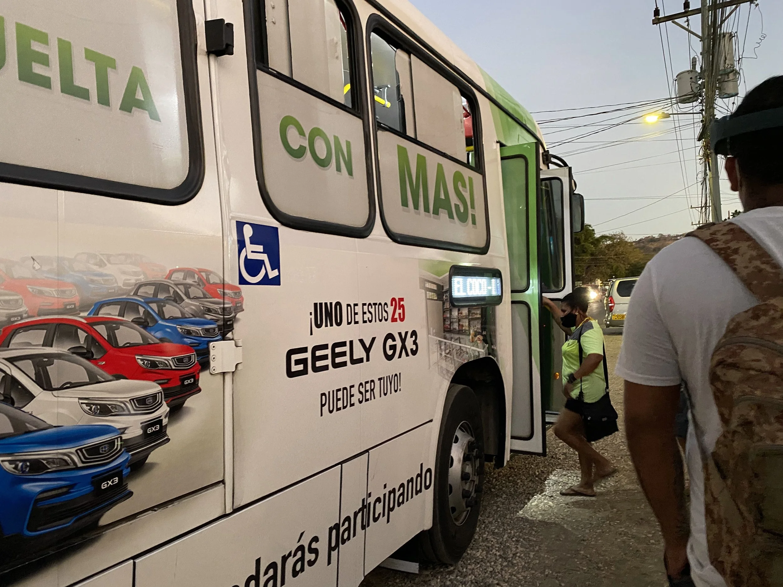 Local bus boarding area in Liberia, Costa Rica, with passengers getting on an evening bus.