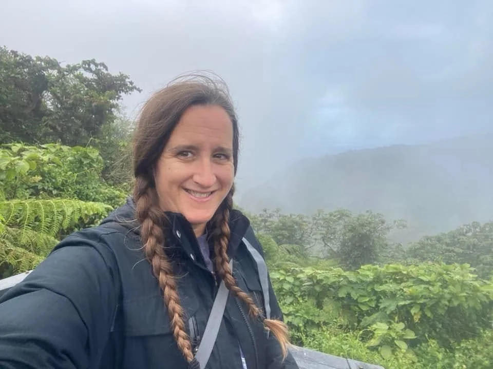 A traveller smiling at a viewpoint in Monteverde Cloud Forest Reserve, surrounded by lush green vegetation and mist-covered mountains in Costa Rica.