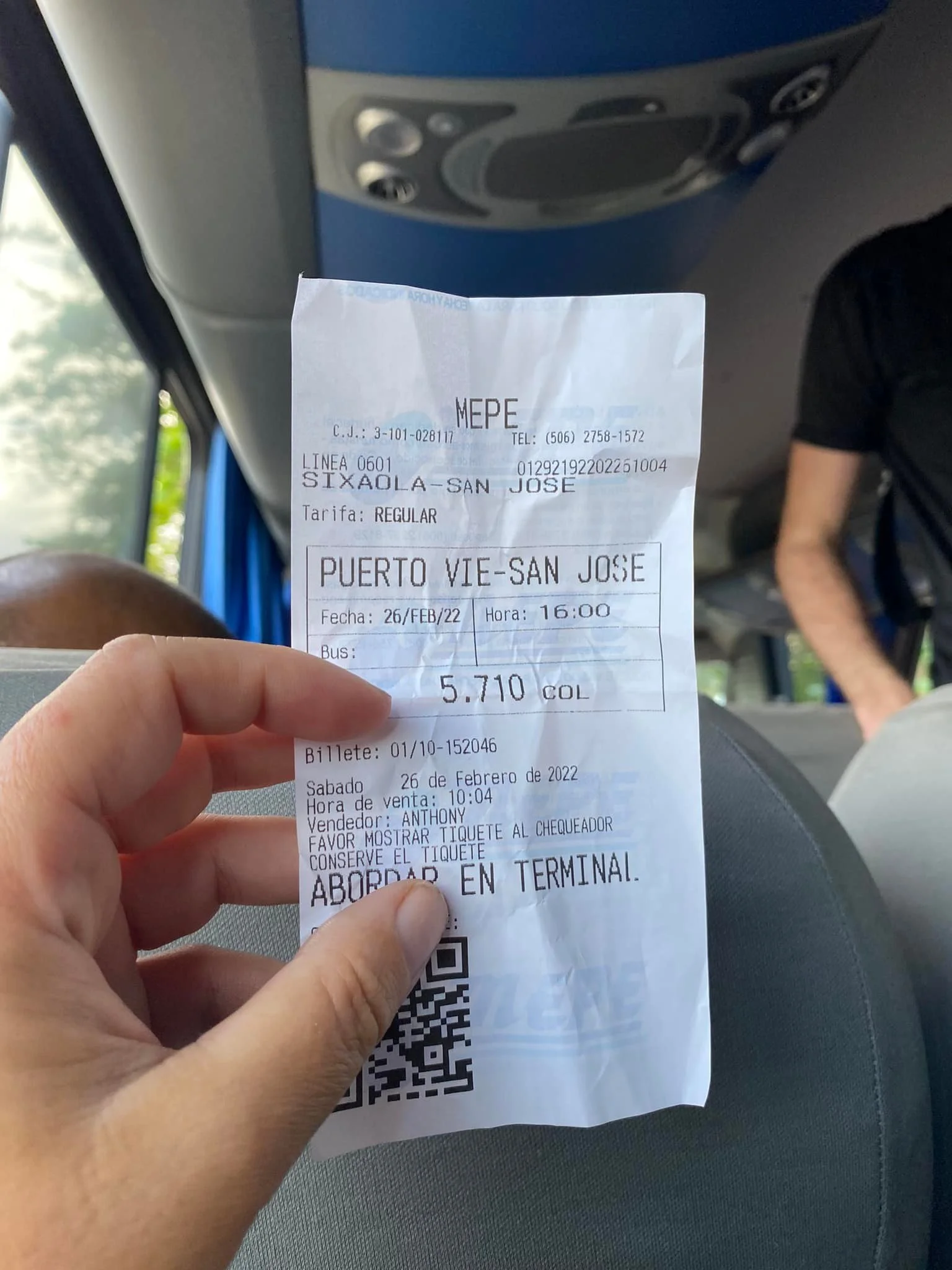 Hand holding a Costa Rican bus ticket while sitting on a bus.
