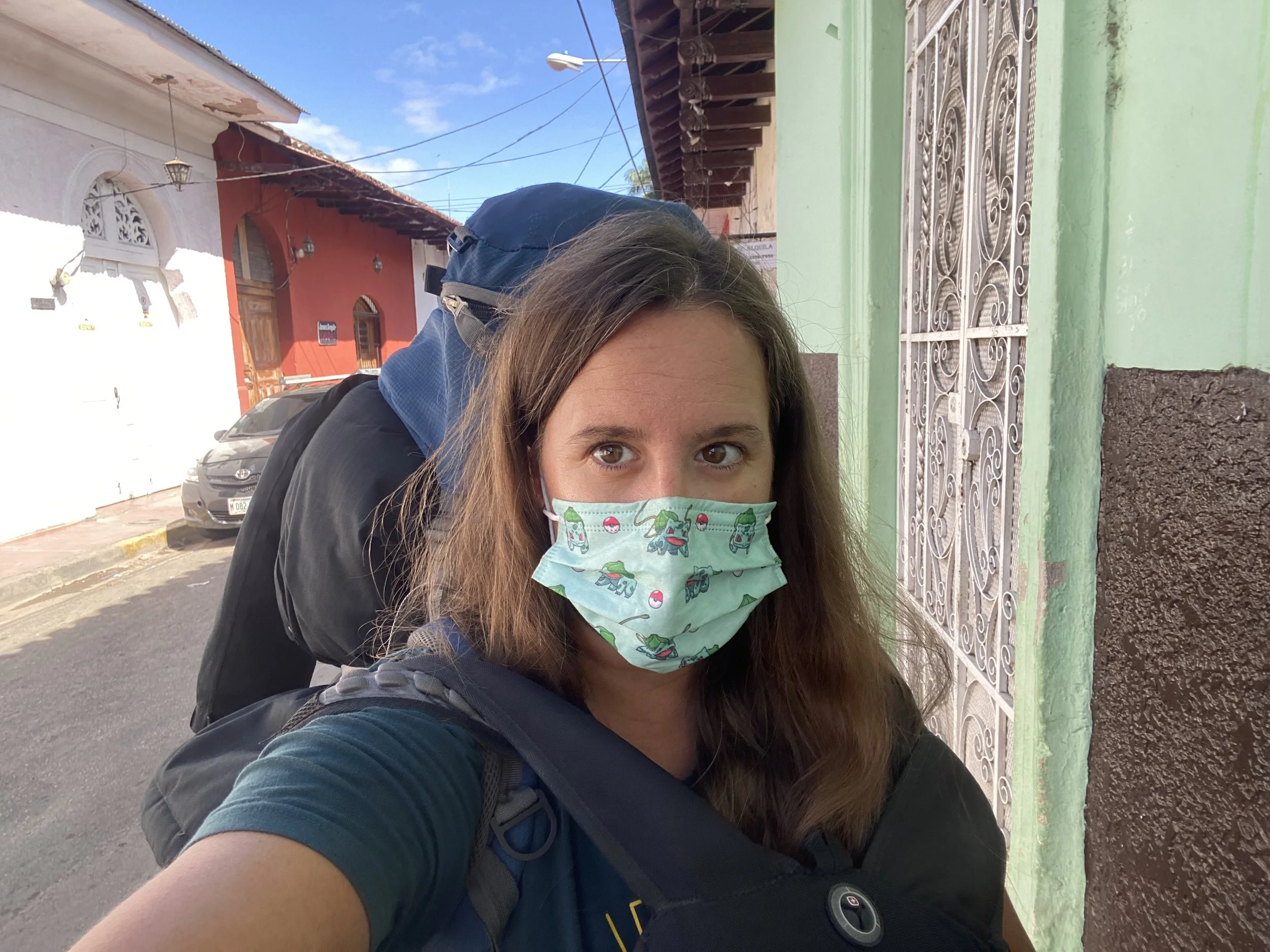 Solo traveler with backpack and face mask arriving in Granada, Nicaragua on a colorful street
