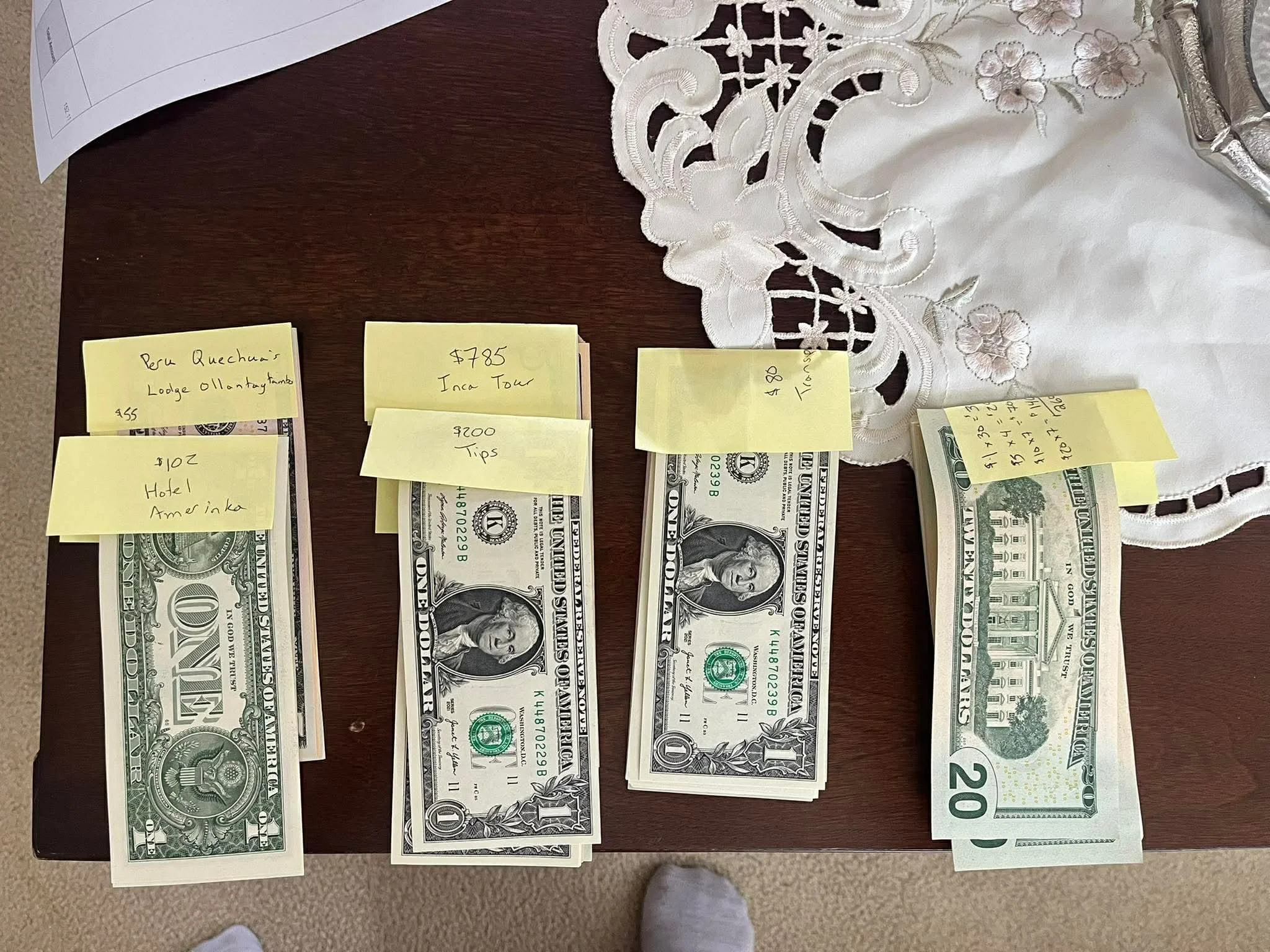 Stacks of U.S. cash separated by travel expense categories with handwritten notes for hotels, the Inca Trail, tips and transportation.