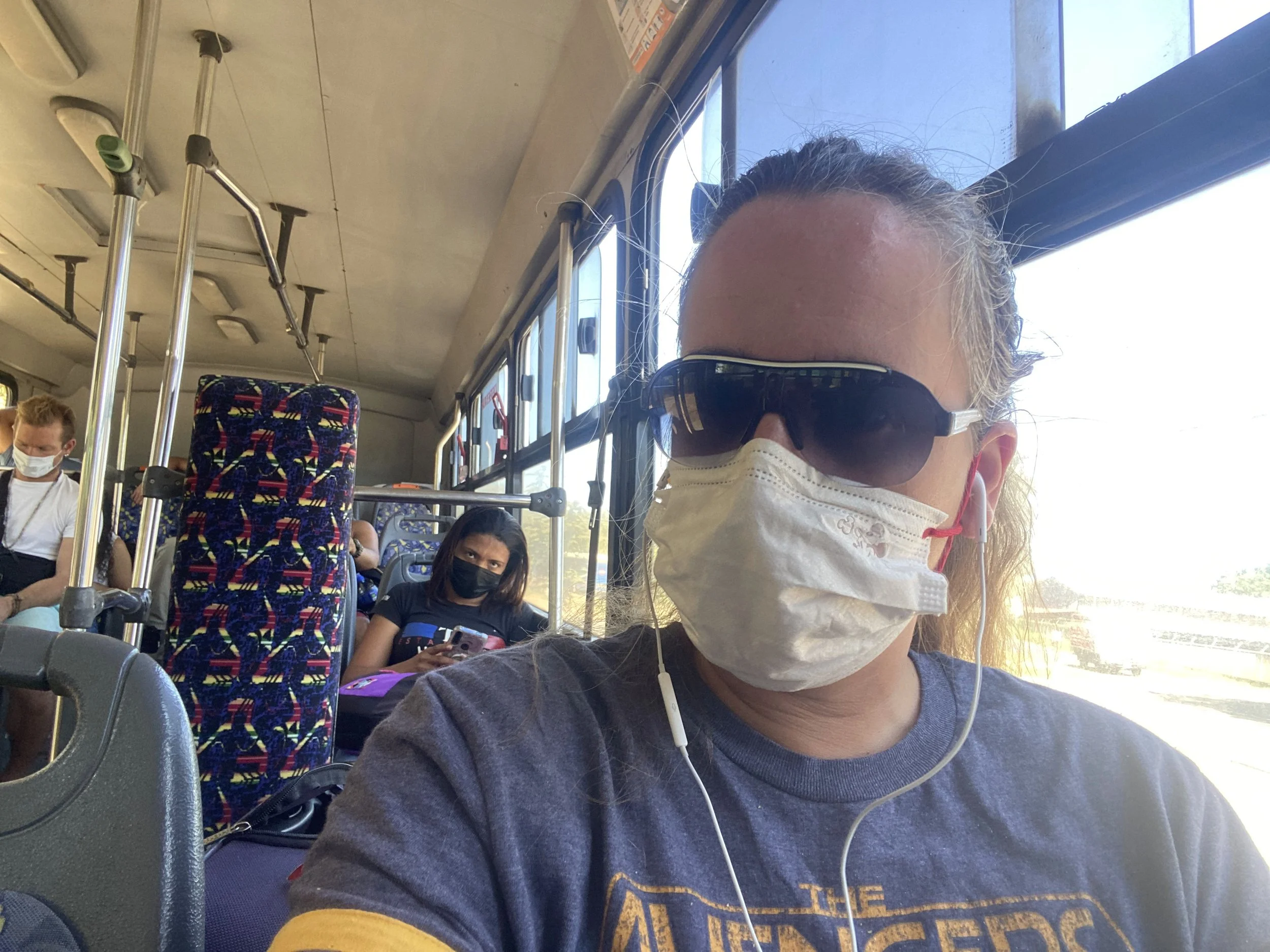 A traveller wearing sunglasses and a face mask sits on a local bus in Costa Rica while travelling from Liberia to Tamarindo.