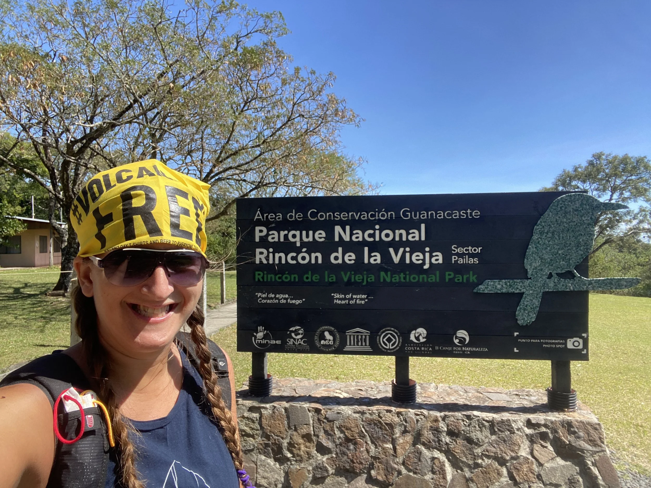 Backpacker standing beside the entrance sign for Rincón de la Vieja National Park near Liberia, Costa Rica.