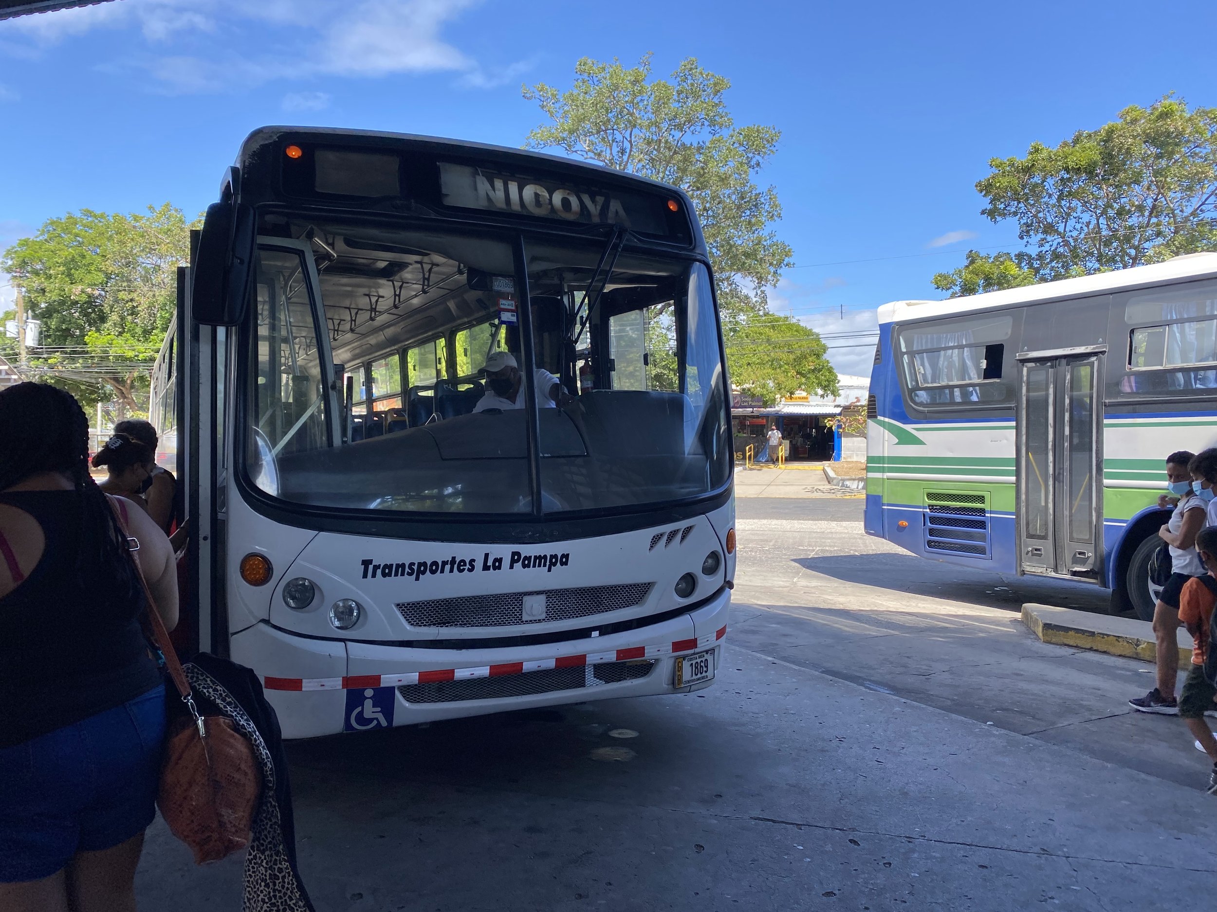 A white local bus at a Costa Rican bus terminal before the journey to the remote sea turtle conservation camp in Cabuyal, Guanacaste.