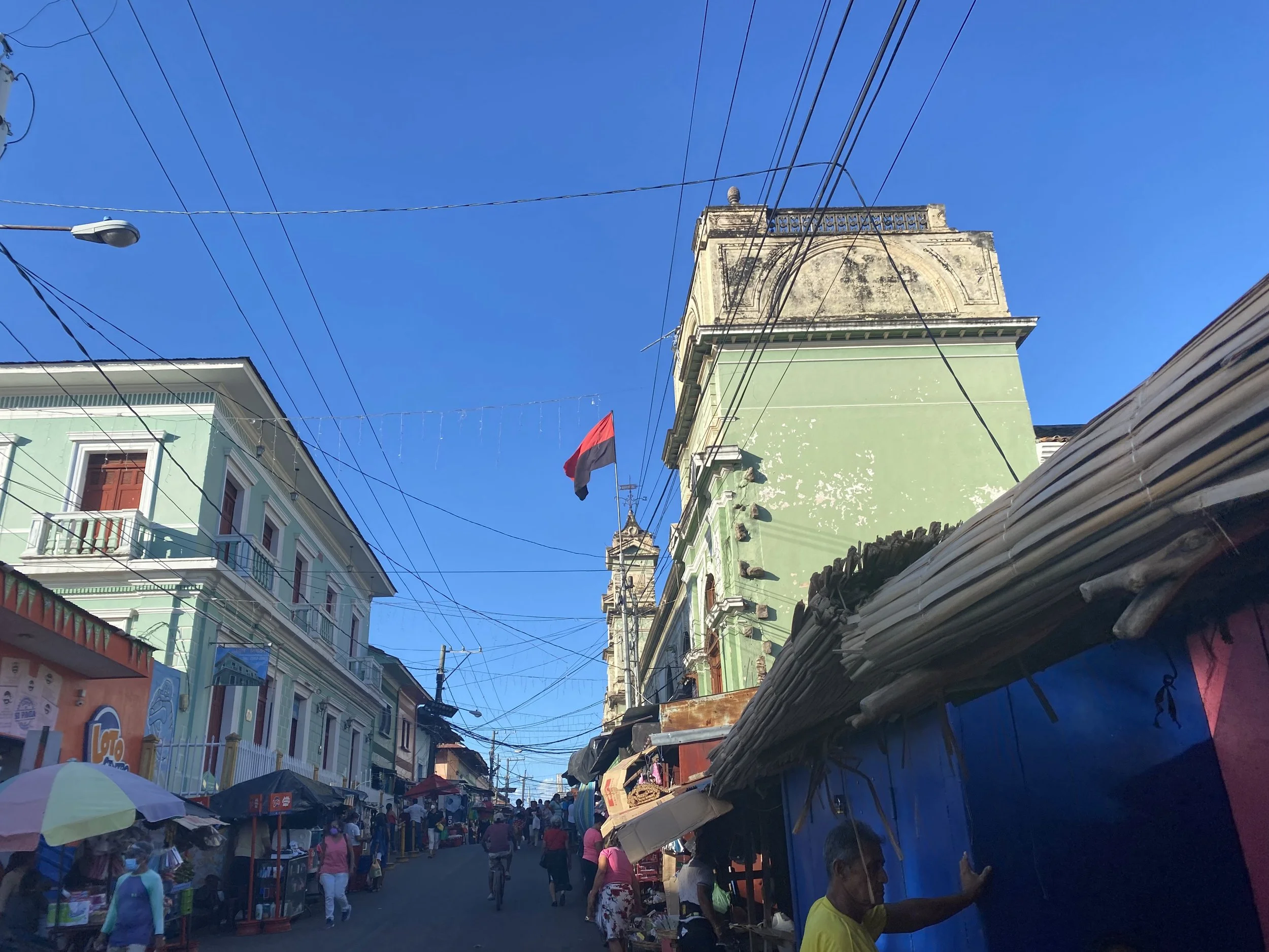 Busy street in Granada Nicaragua with colorful colonial buildings, local vendors, and pedestrians