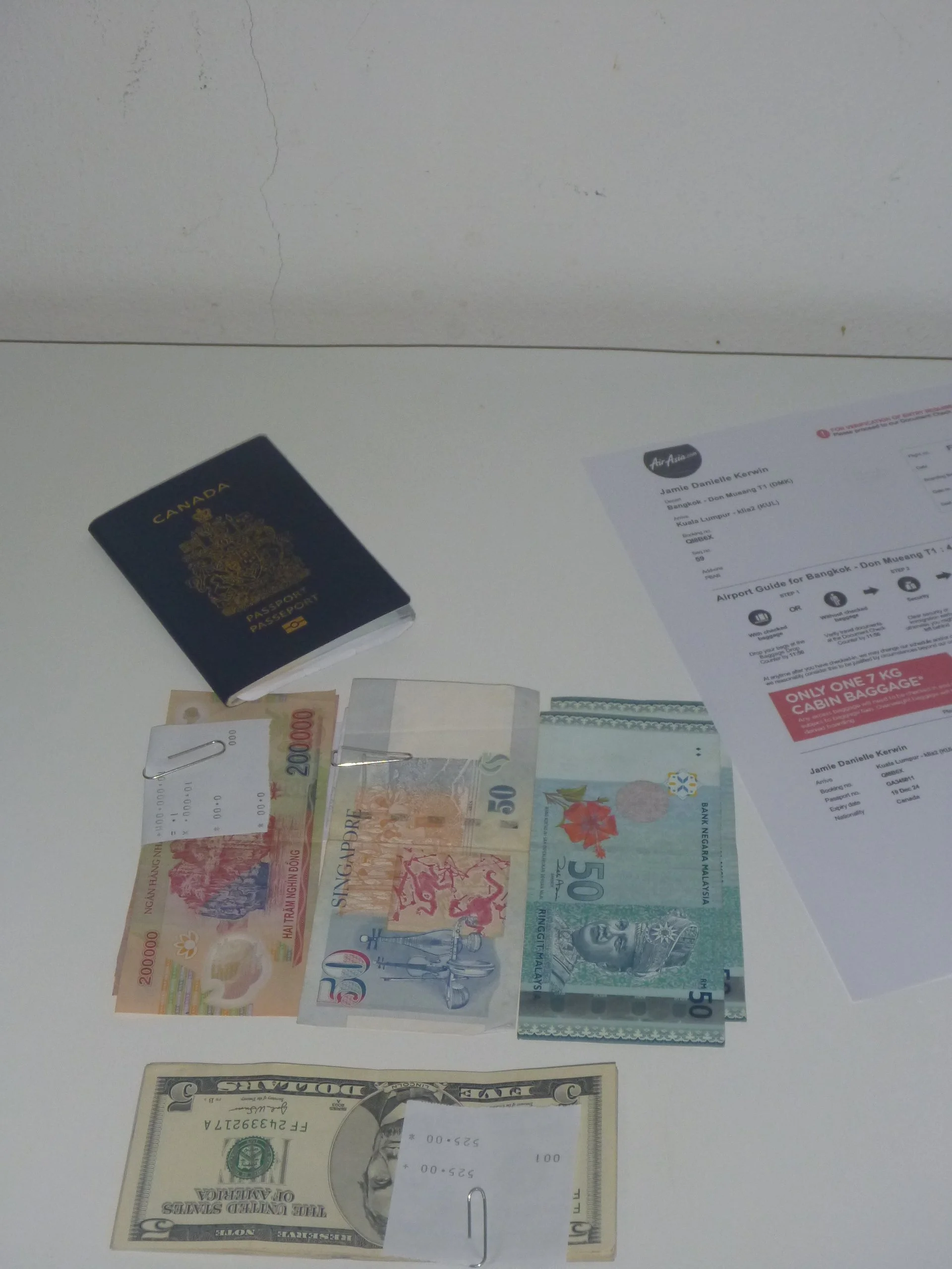 Canadian passport, multiple international currencies, boarding pass, and travel documents prepared before an international trip to illustrate comparing exchange rates and organizing travel essentials.