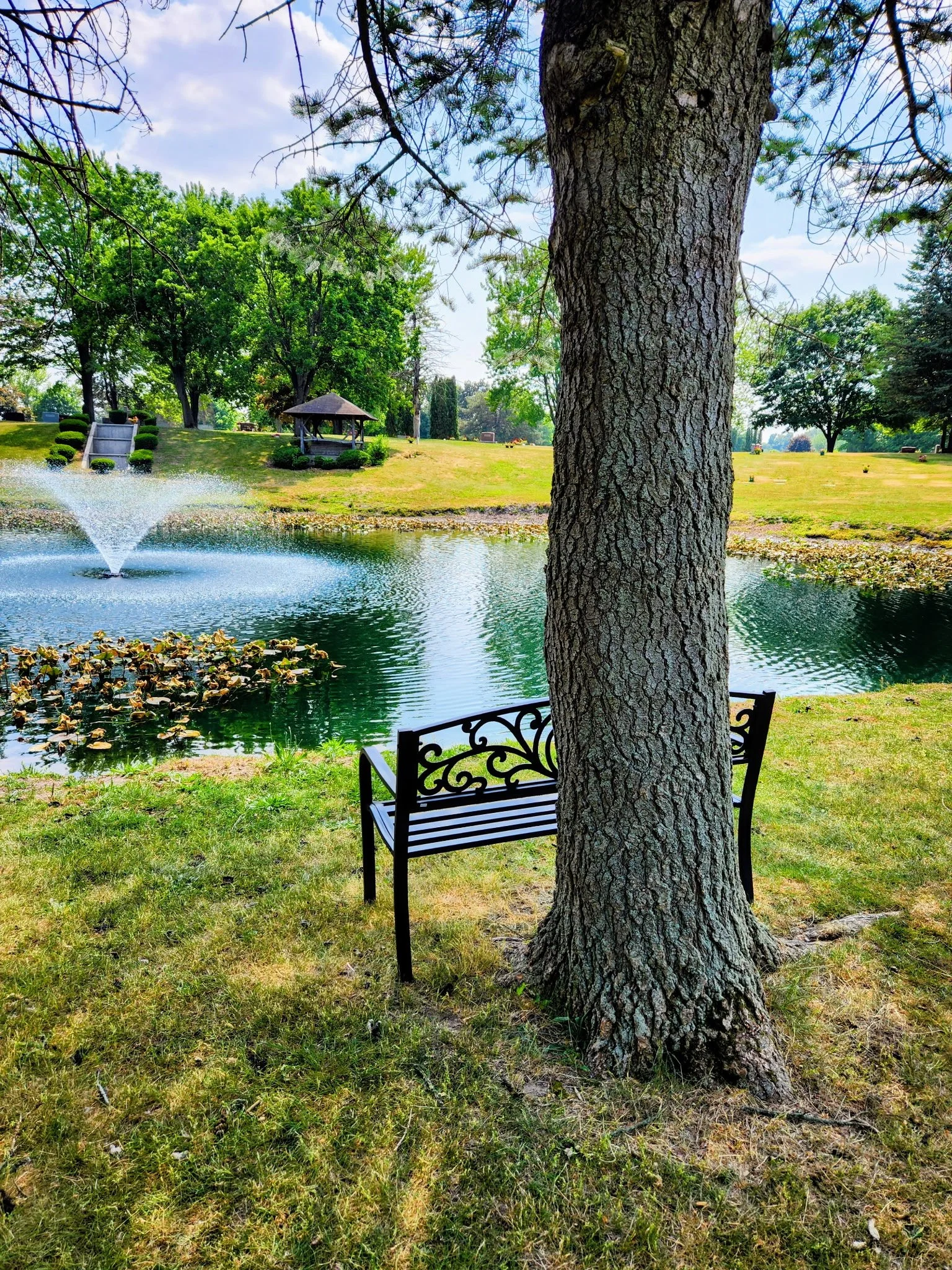 Bench near pond and fountain in the cemetery grounds