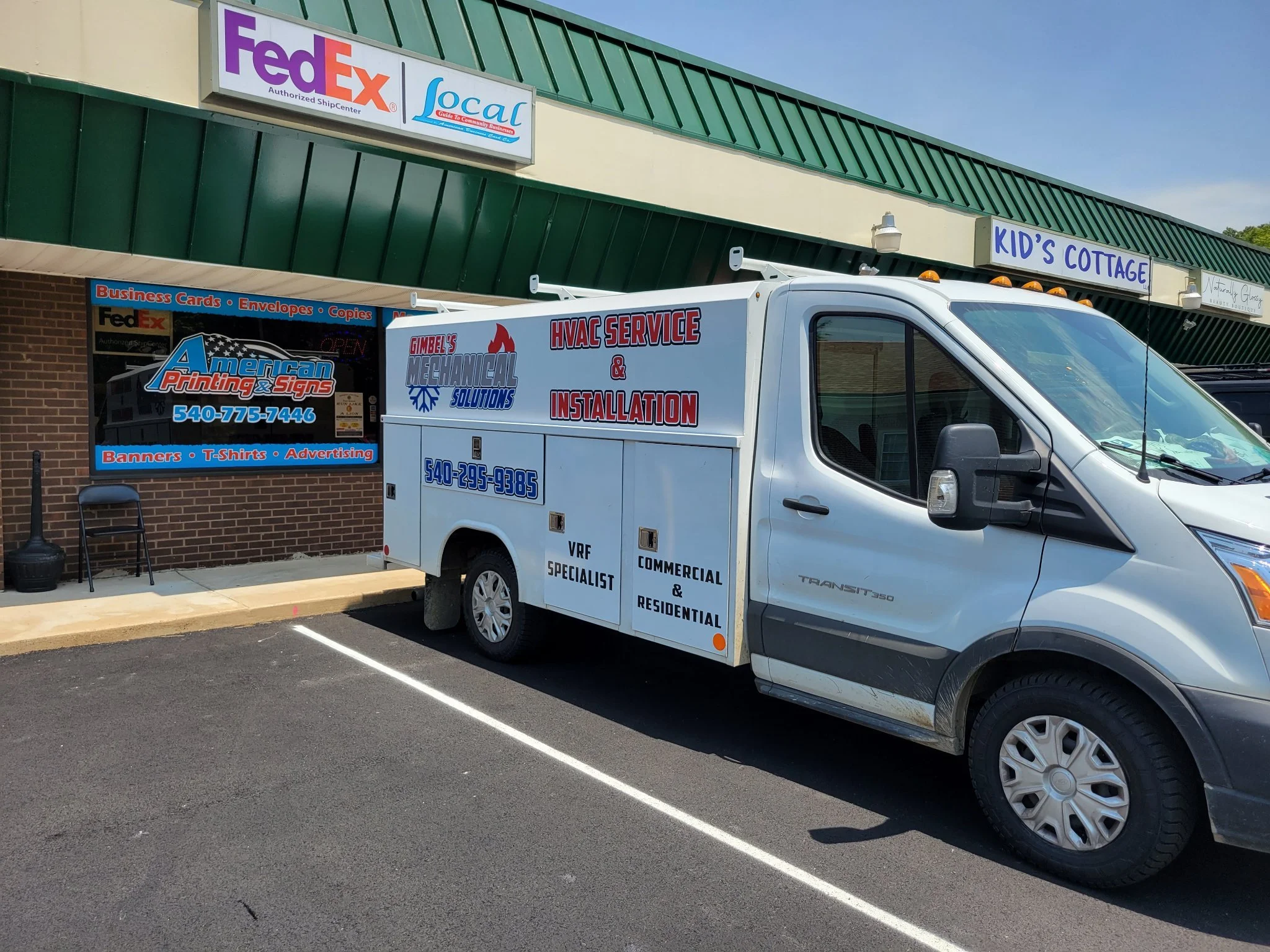 A vehicle wrap for Gimbel's Mechanical Solutions parked in front of American Printing & Signs. The service van is branded with Gimbel's logo and contact information.