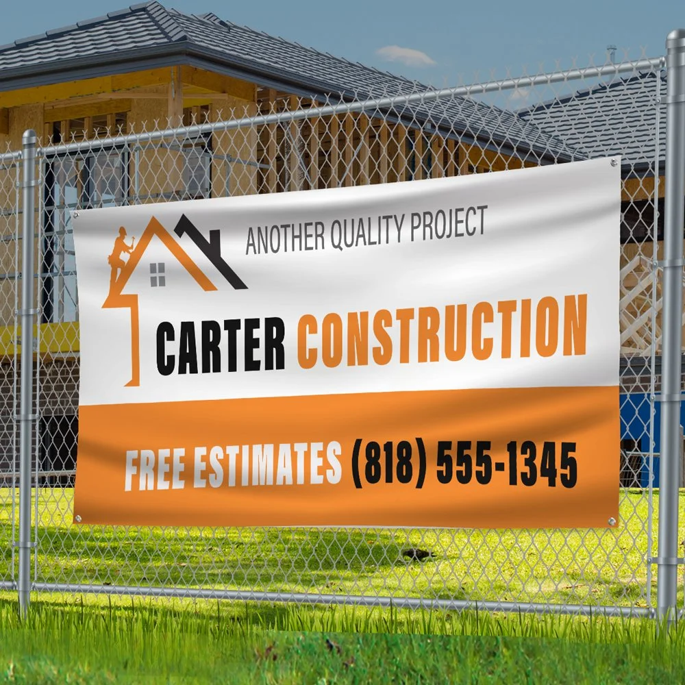 A construction site fence with a custom designed vinyl banner that reads 'Carter Construction' offering free estimates and indicating it is another quality project, with a phone number and a house framework under construction in the background.