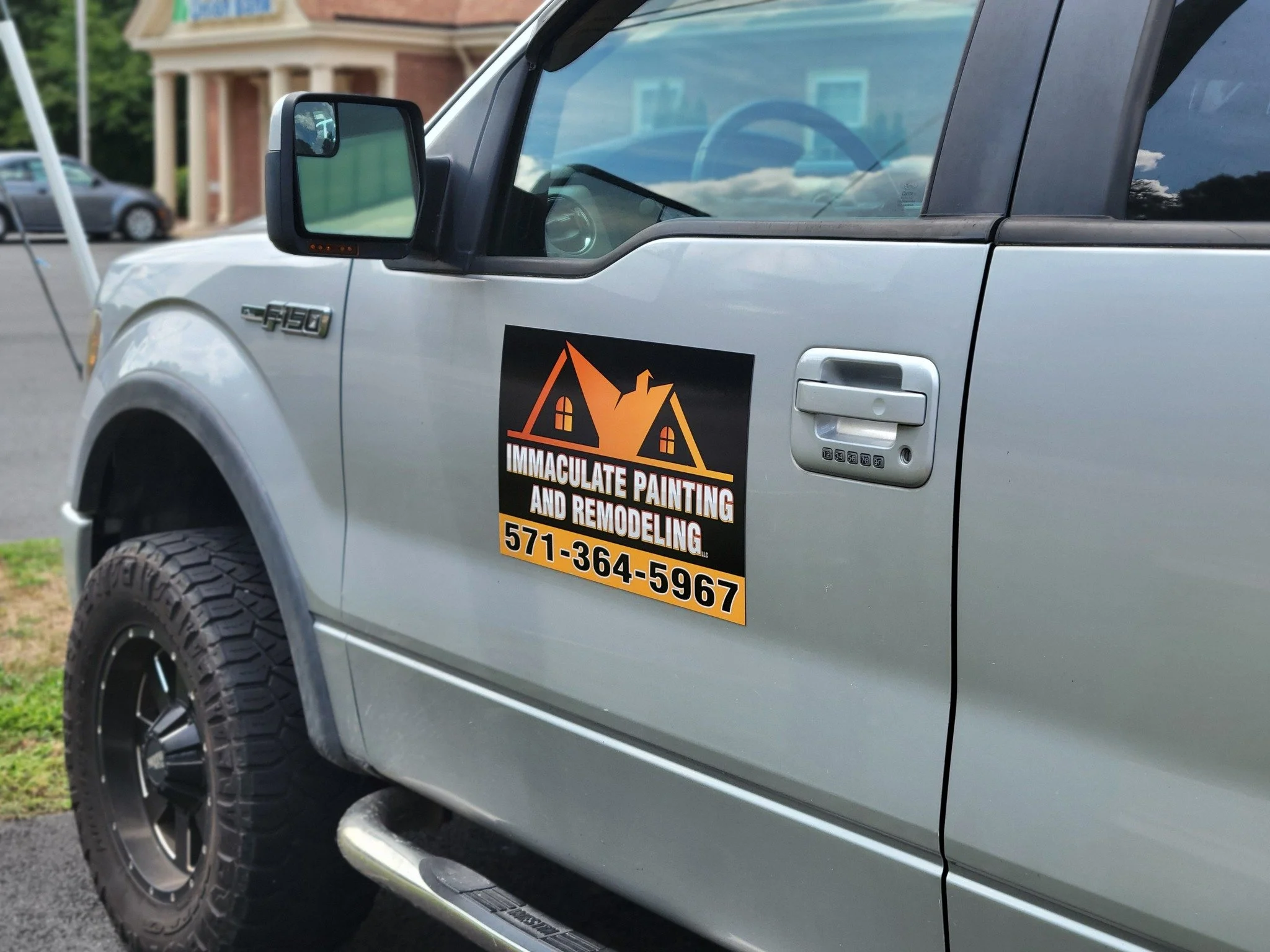 Vehicle Magnet on the door of a Silver Ford F-150 truck advertising immaculate painting and remodeling, including a phone number.