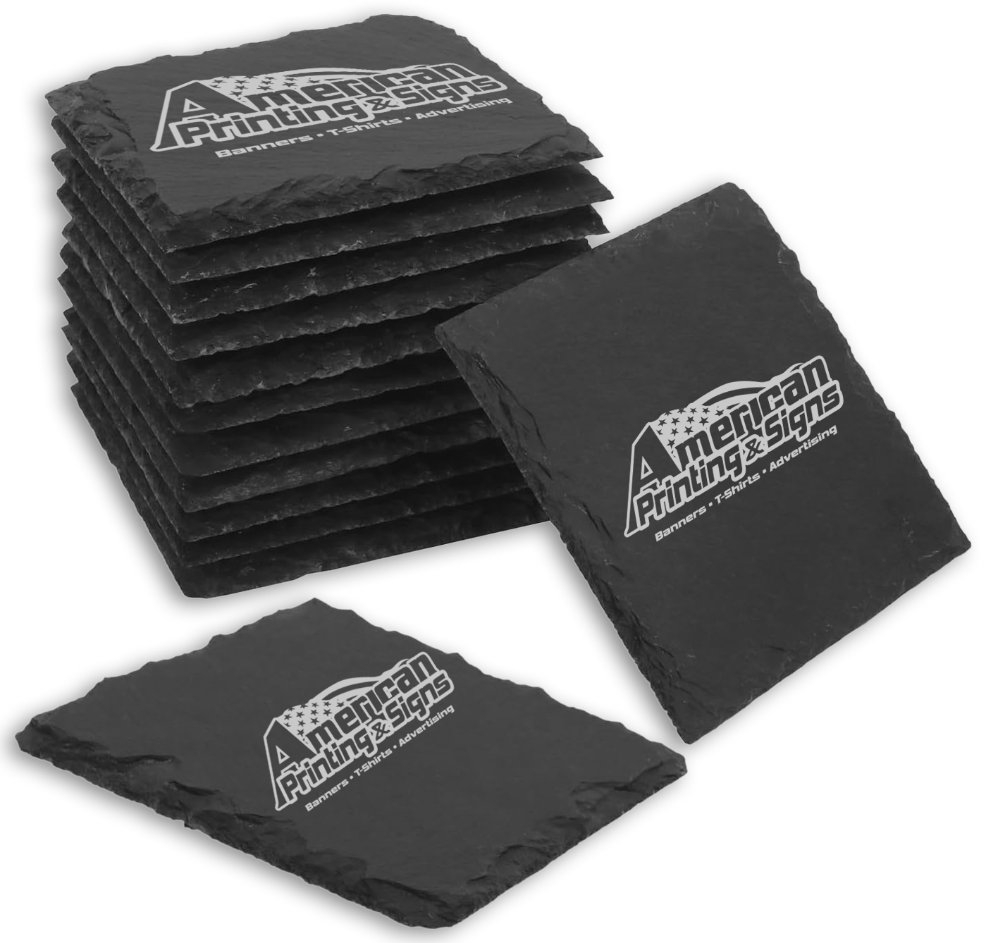 Stack of black slate tiles with a custom engraved logo that reads 'American Printing & Signs' and lists services such as banners, T-shirts, and advertising.