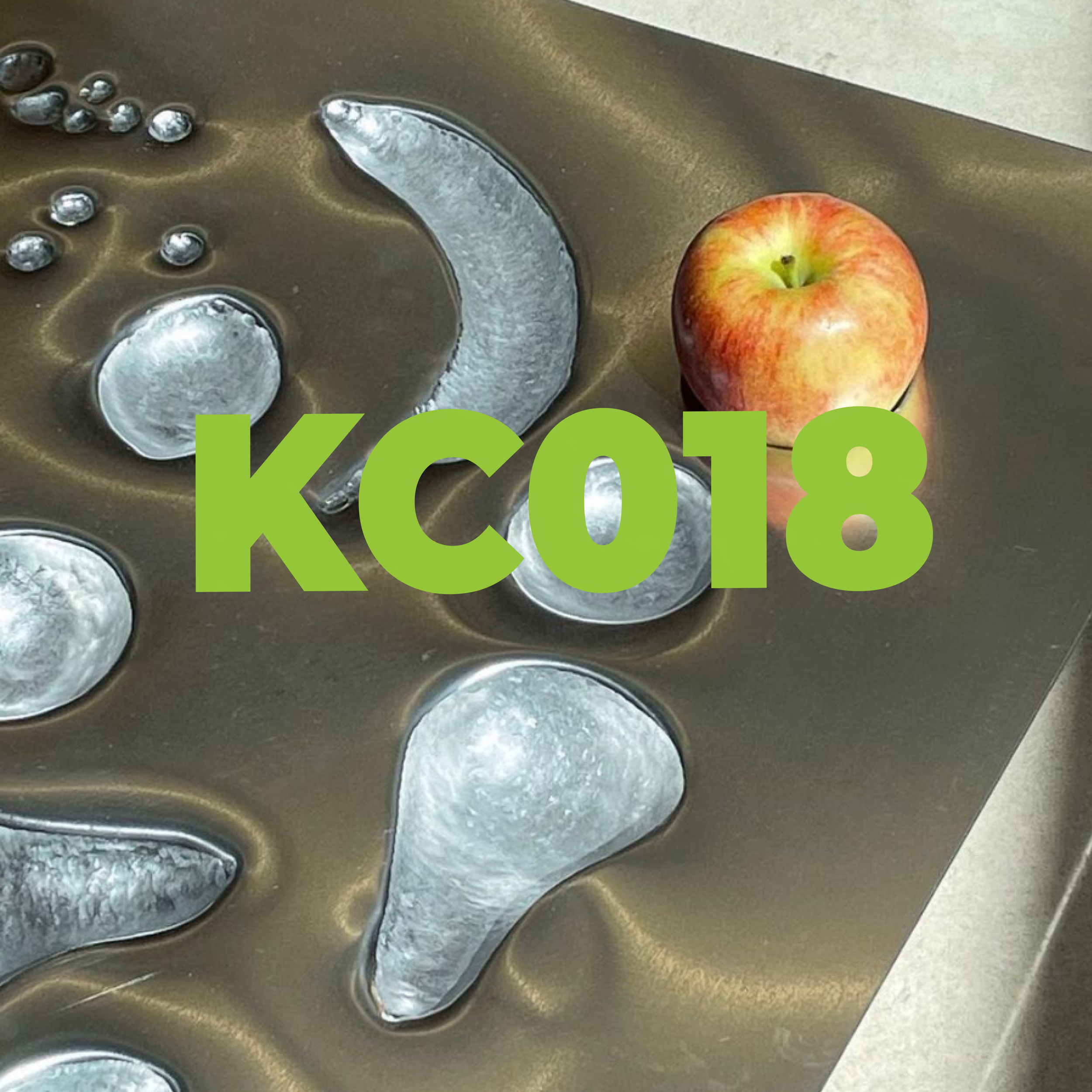 An apple resting on a metallic ice tray with various ice formations and the text 'KC018' overlayed on the image.