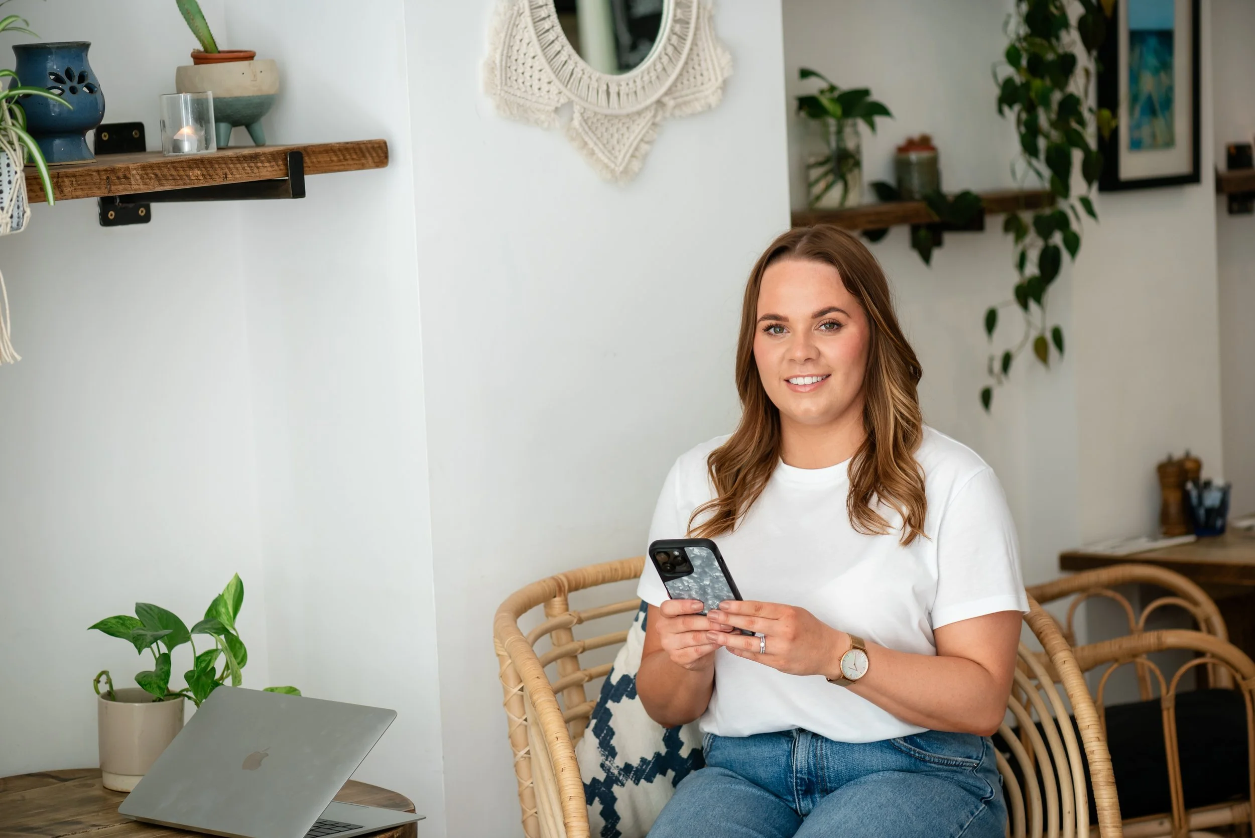 Grace Price from Silver Lining Social holding her phone while working on digital marketing content