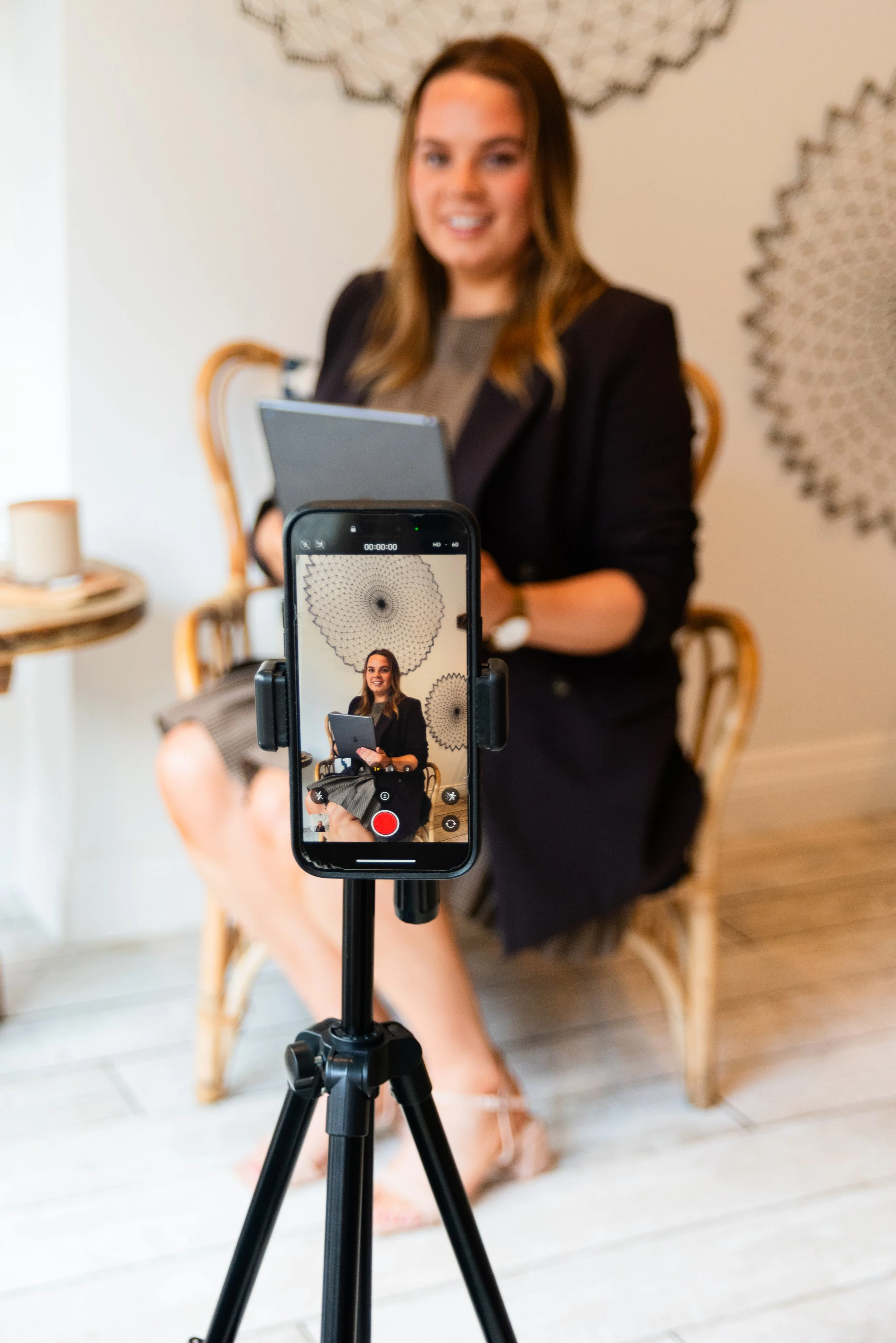 Grace from Silver Lining Social filming social media video content on a smartphone and tripod in a bright studio space