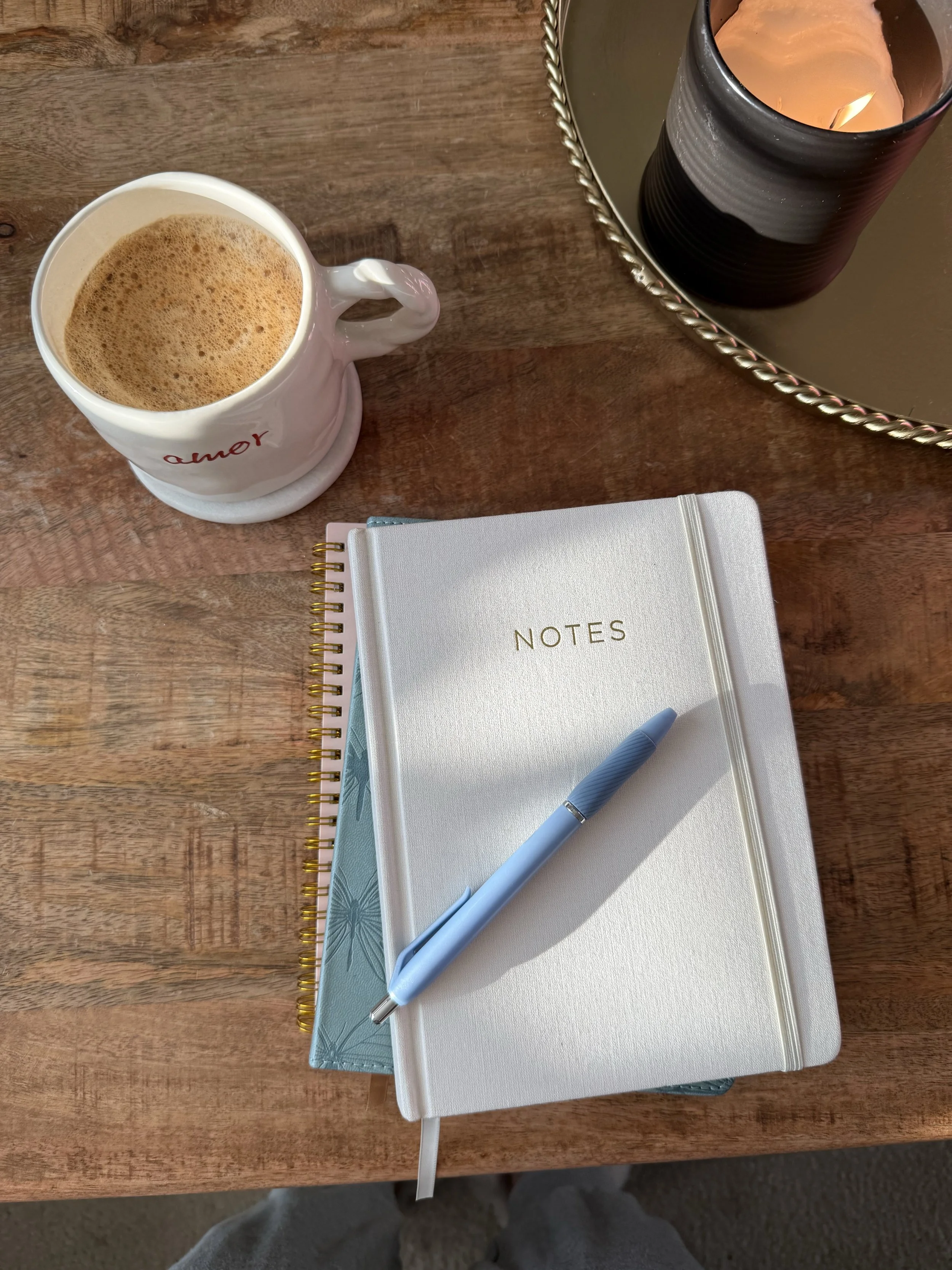 Styled desk flatlay with a coffee, notebooks and candle, small business workspace aesthetic