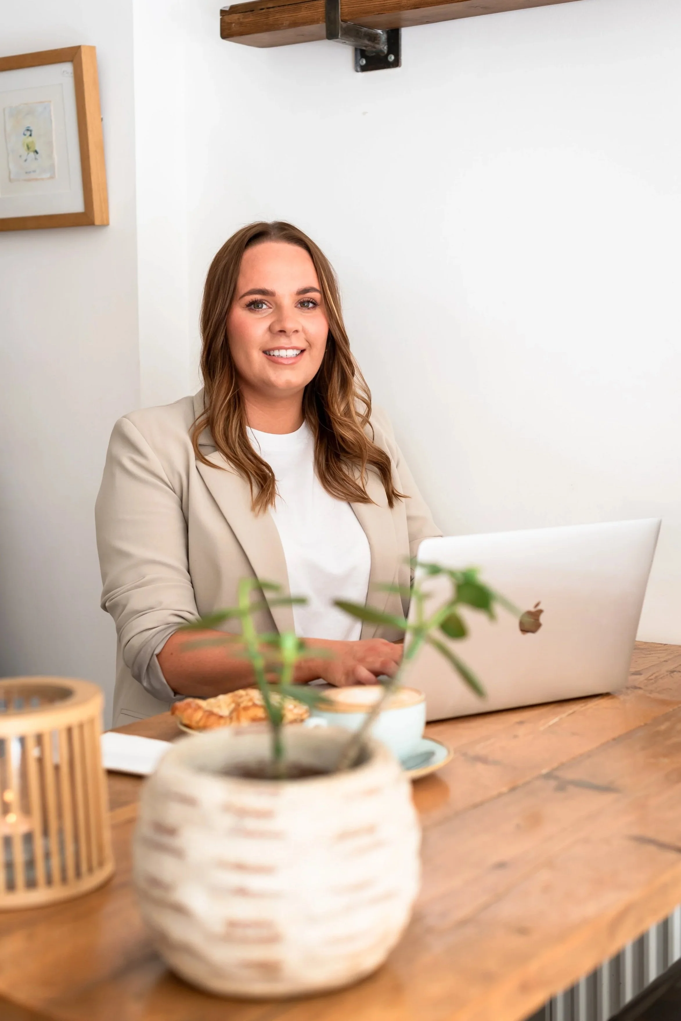 Grace from Silver Lining Social working on a laptop in a bright modern home workspace with plants