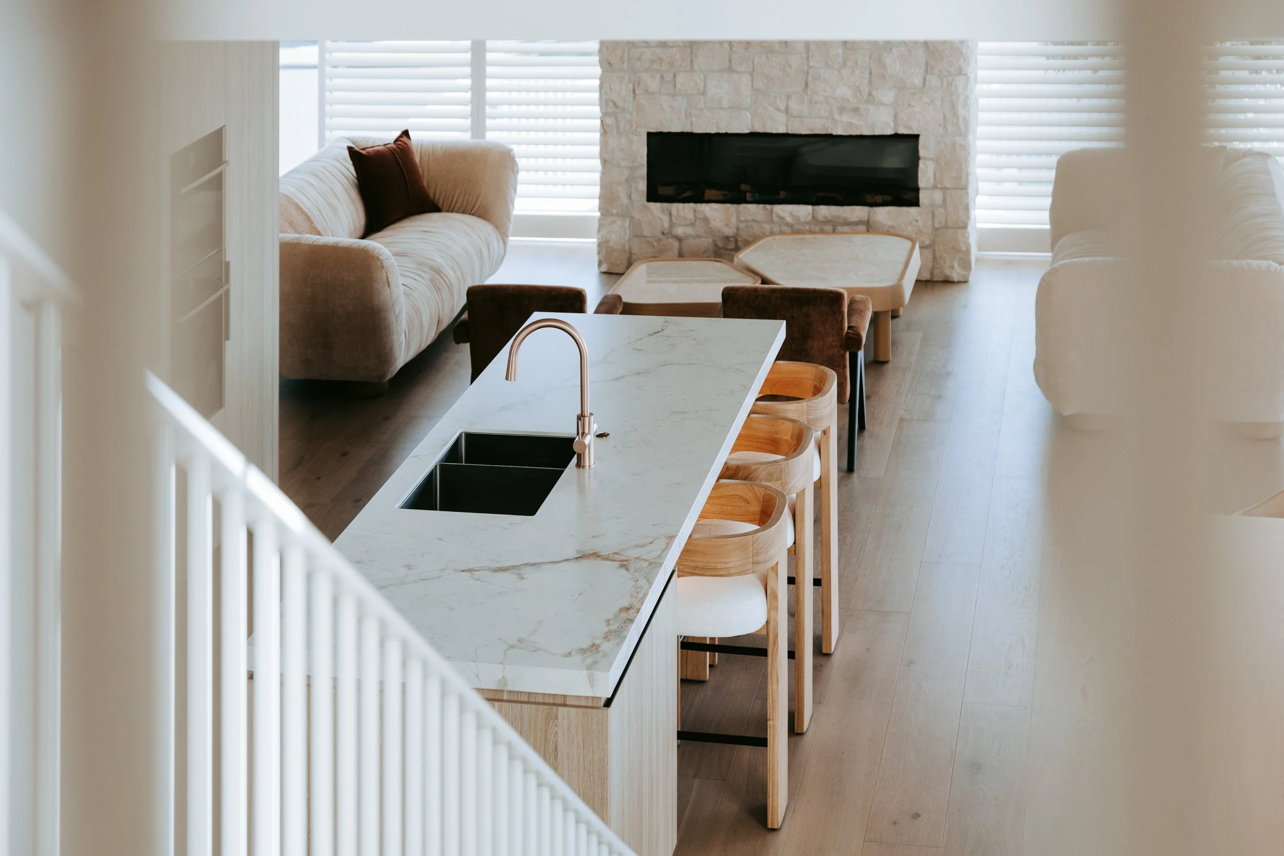 View from stairs to kitchen island with stone bench in Palm Springs Mount Maunganui home renovation