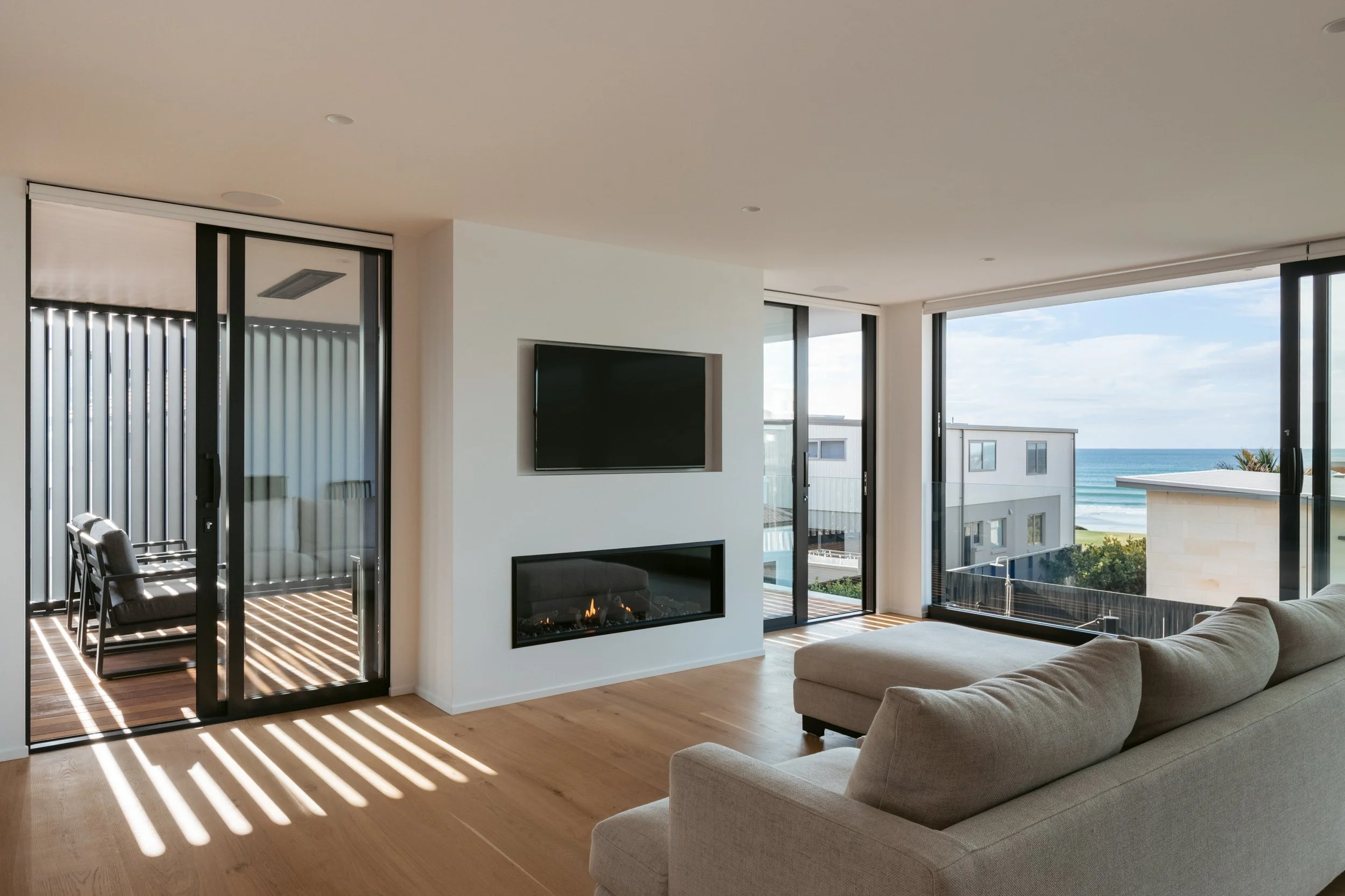 Open-plan living area in Beachside Minimalism Tauranga home with panoramic glazing and beach views