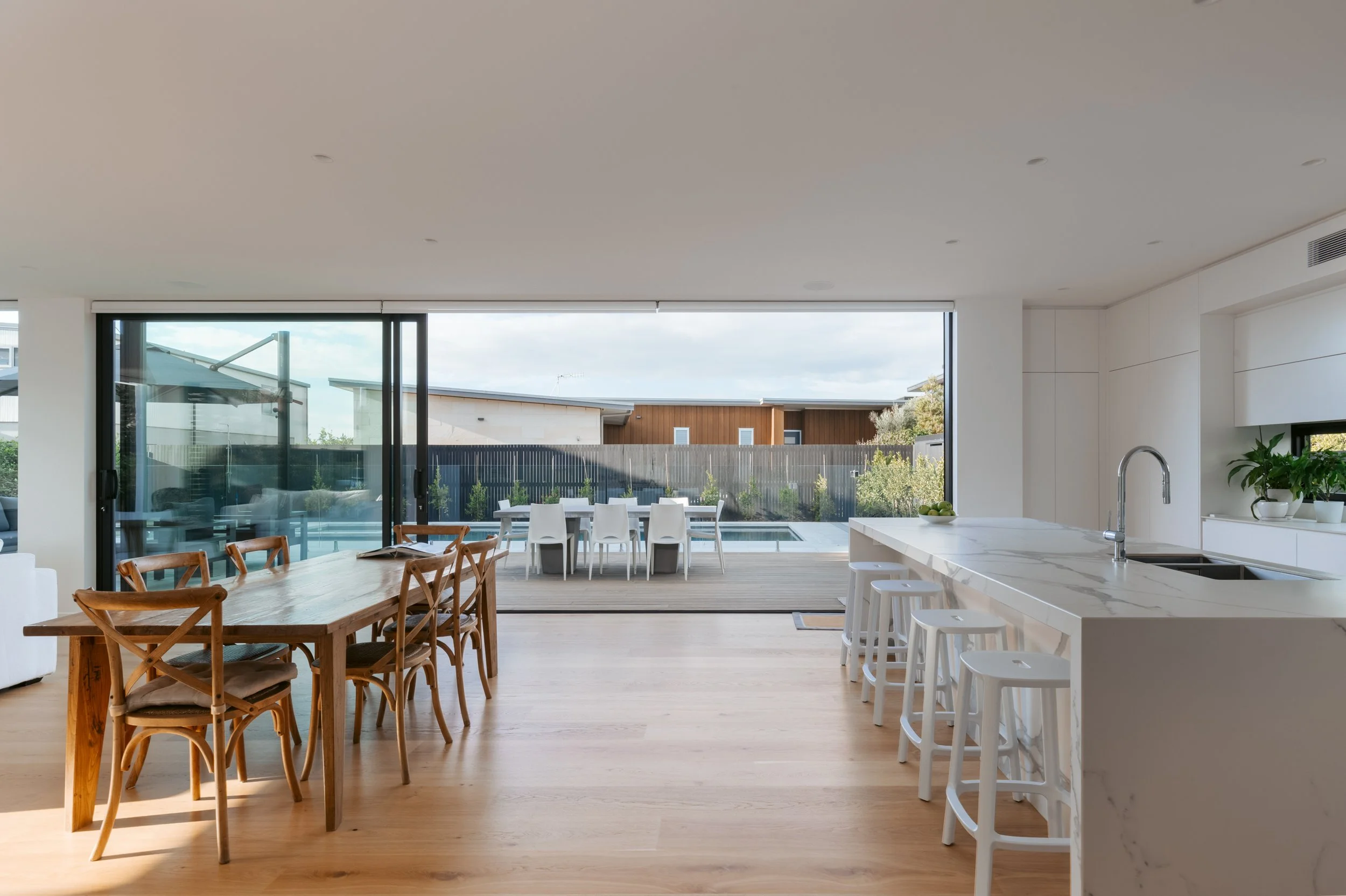 Dining area in Beachside Minimalism Tauranga home featuring open-plan layout and poolviews