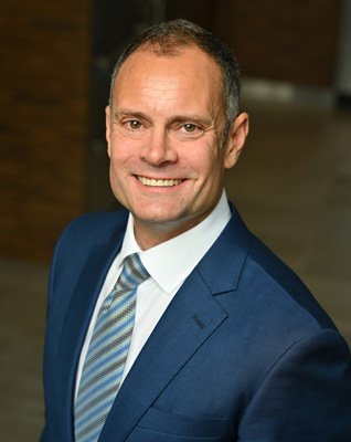 Man in a blue suit smiling at the camera.