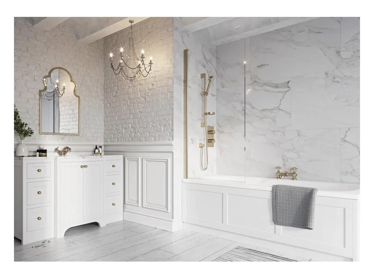 A luxurious bathroom featuring a white vanity with drawers, a decorative mirror, a chandelier, a marble-framed bathtub, a brass shower with glass panel, and a gray towel hanging over the bathtub.