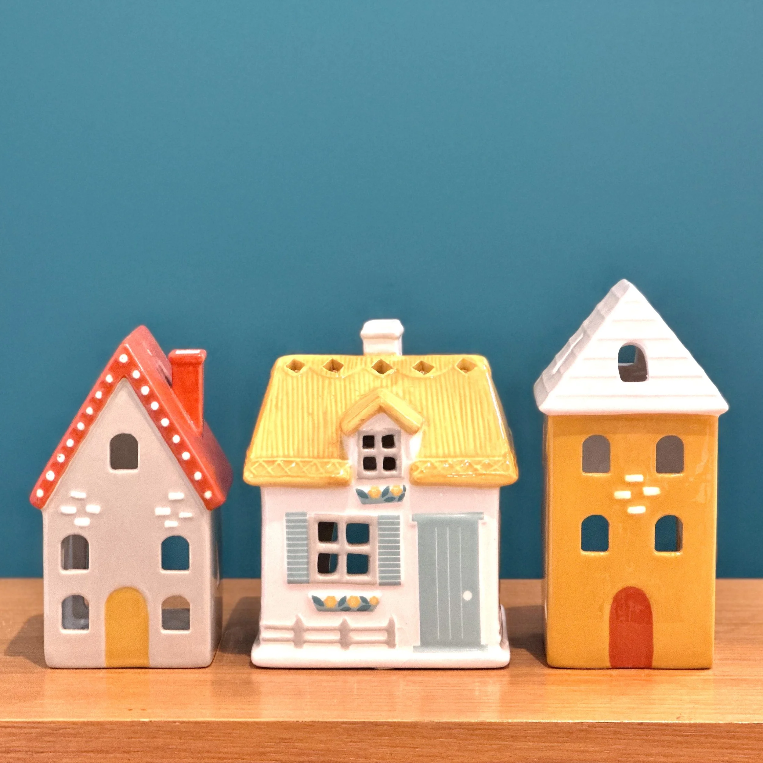 Image of a row of ceramic houses on a shelf, against a teal coloured wall