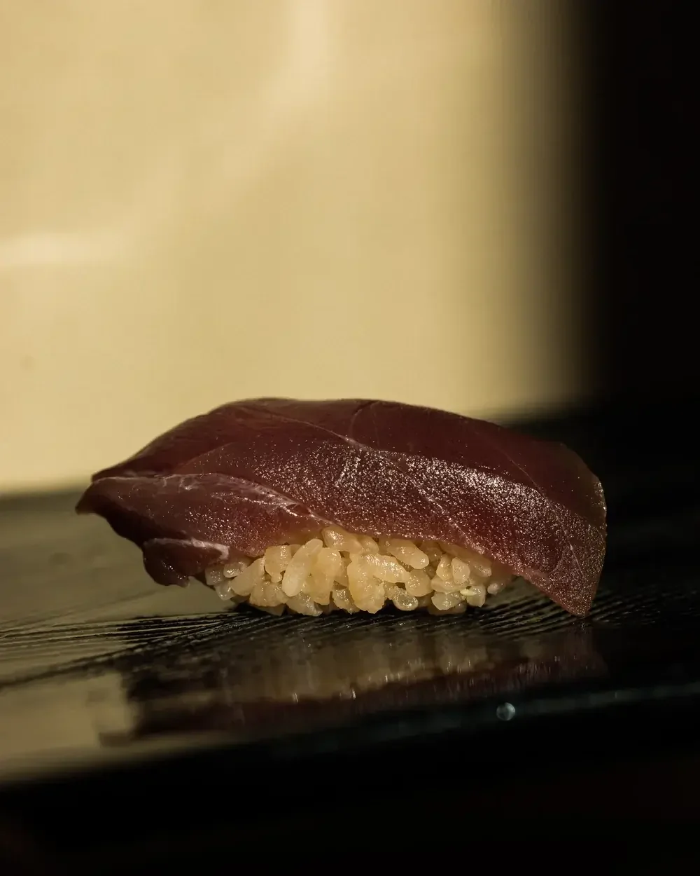 Maguro nigiri sushi on a dark surface.