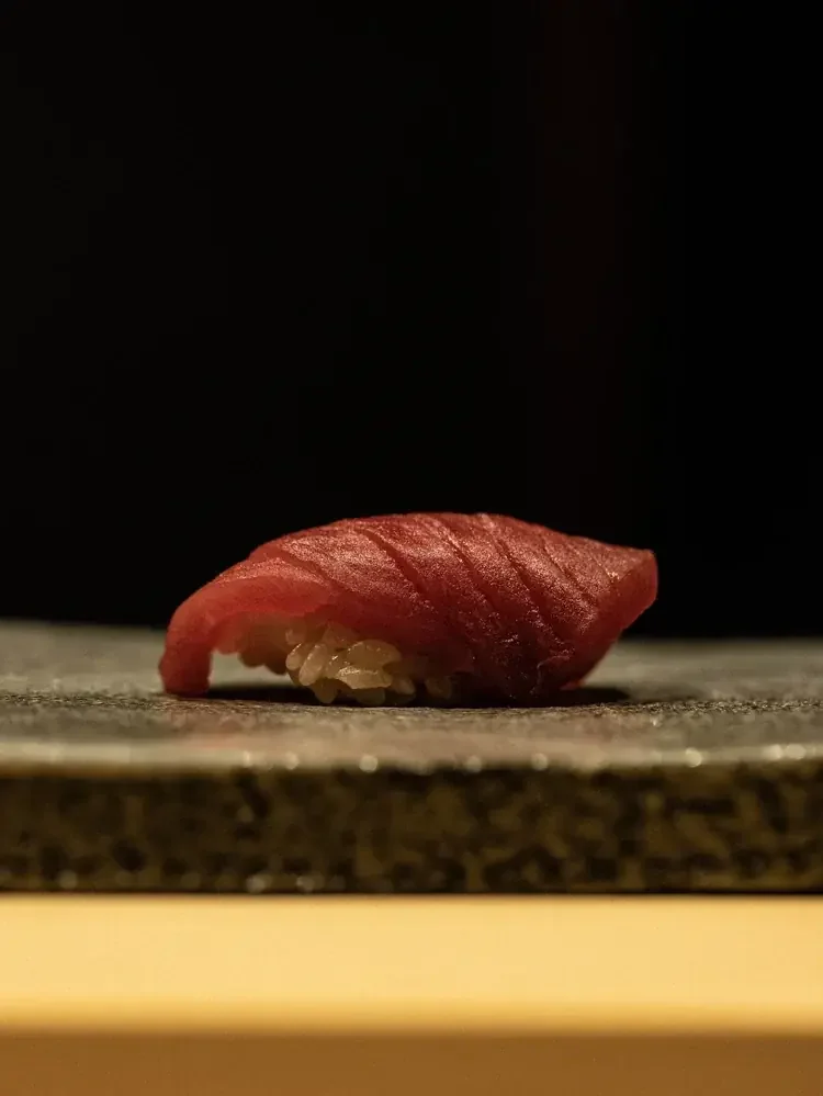 Tuna nigiri on a textured stone plate.