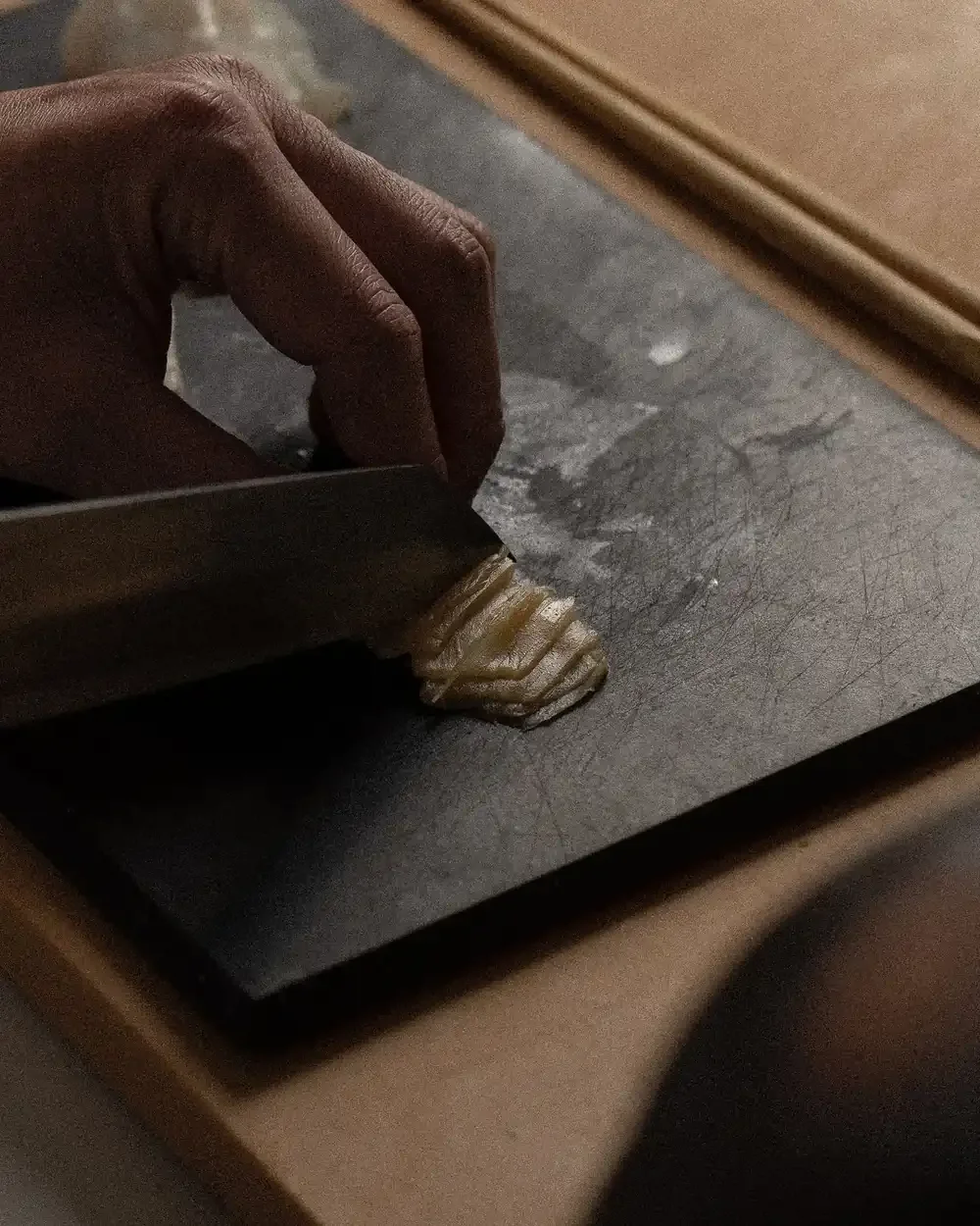 Chef’s hand precisely slicing a small, layered ingredient