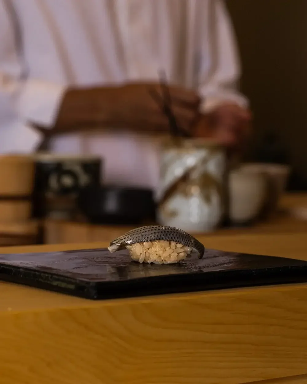 Kohada nigiri sushi on a black stone plate.