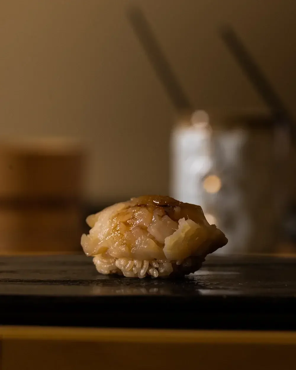 Seared engawa nigiri sushi on a dark surface.