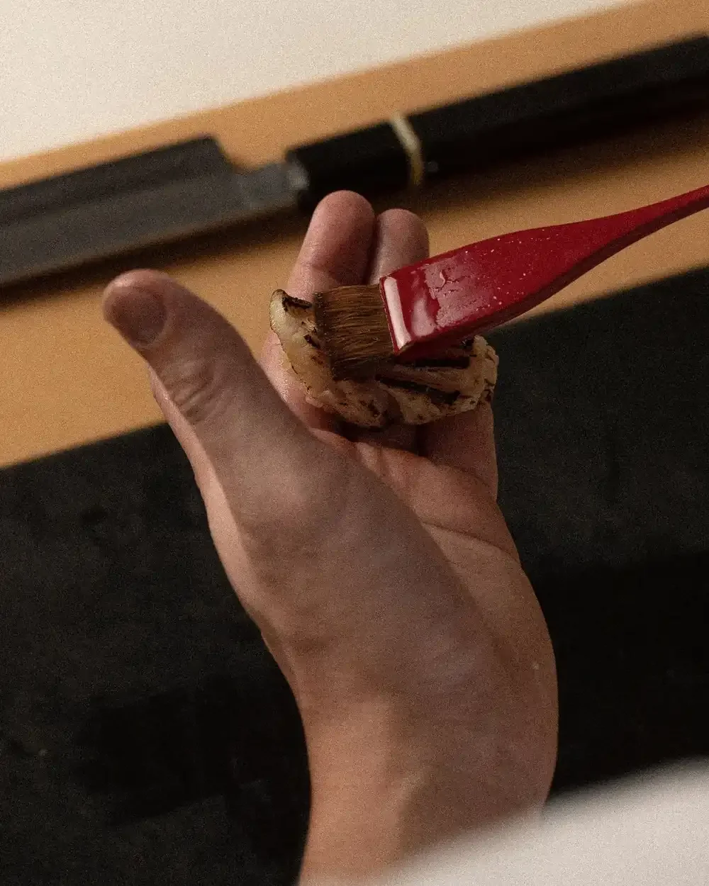 A chef glazes seared nigiri by hand.