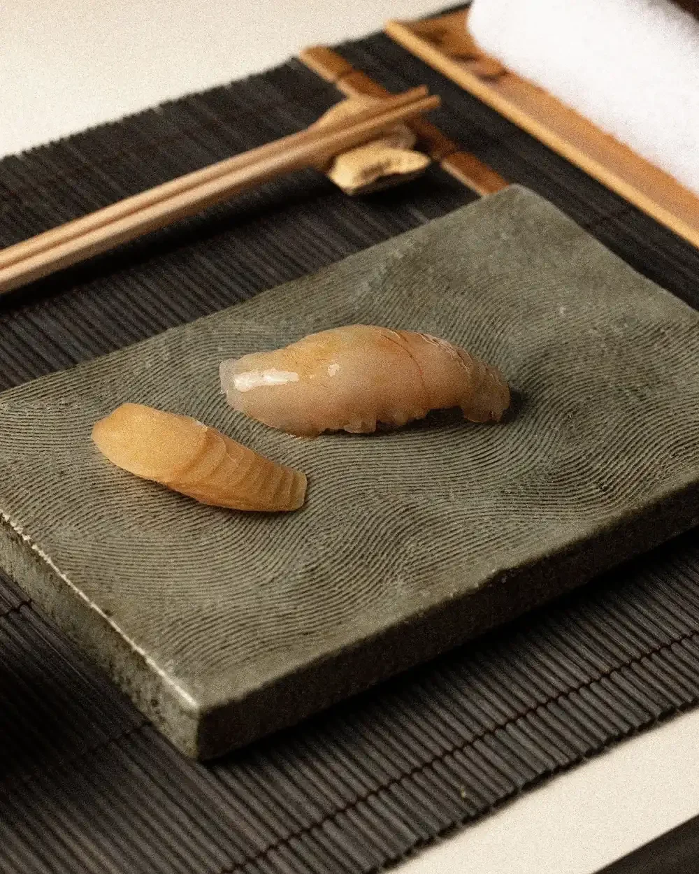 A single piece of white fish nigiri and a slice of pickled ginger.